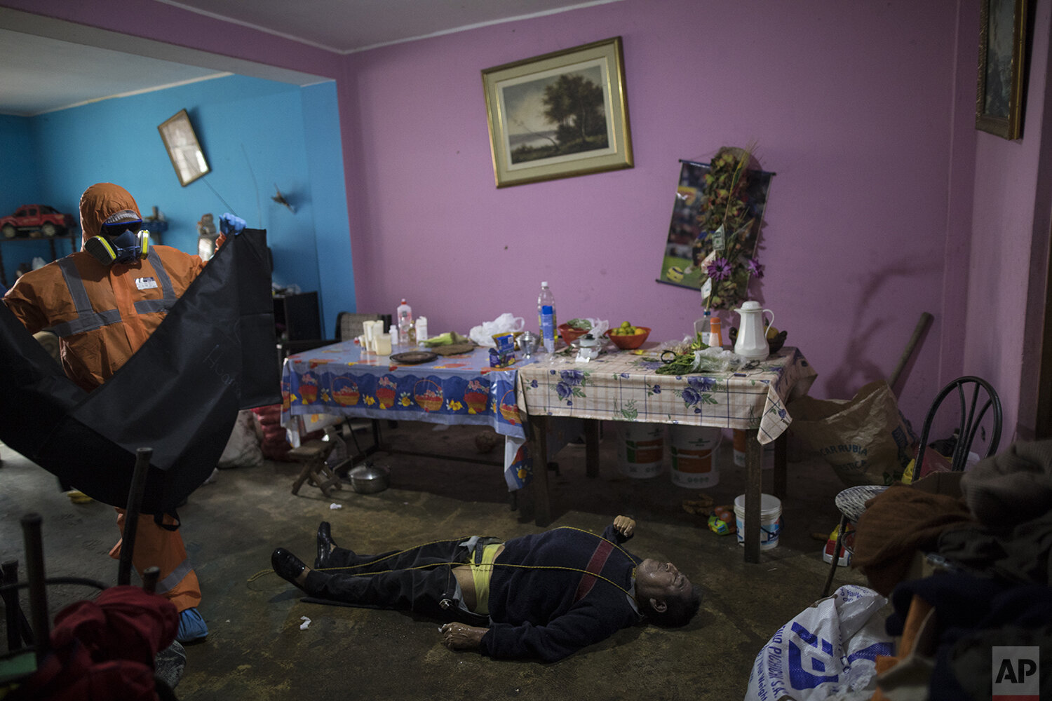  In this photo from May 5, 2020, Luis Zerpa, 21, prepares to collect the corpse of Faustino Lopez, 68, who committed suicide inside his home in Lima, Peru. Faustino Lopez's son, Jorge Lopez, told The Associated Press that his father committed suicide