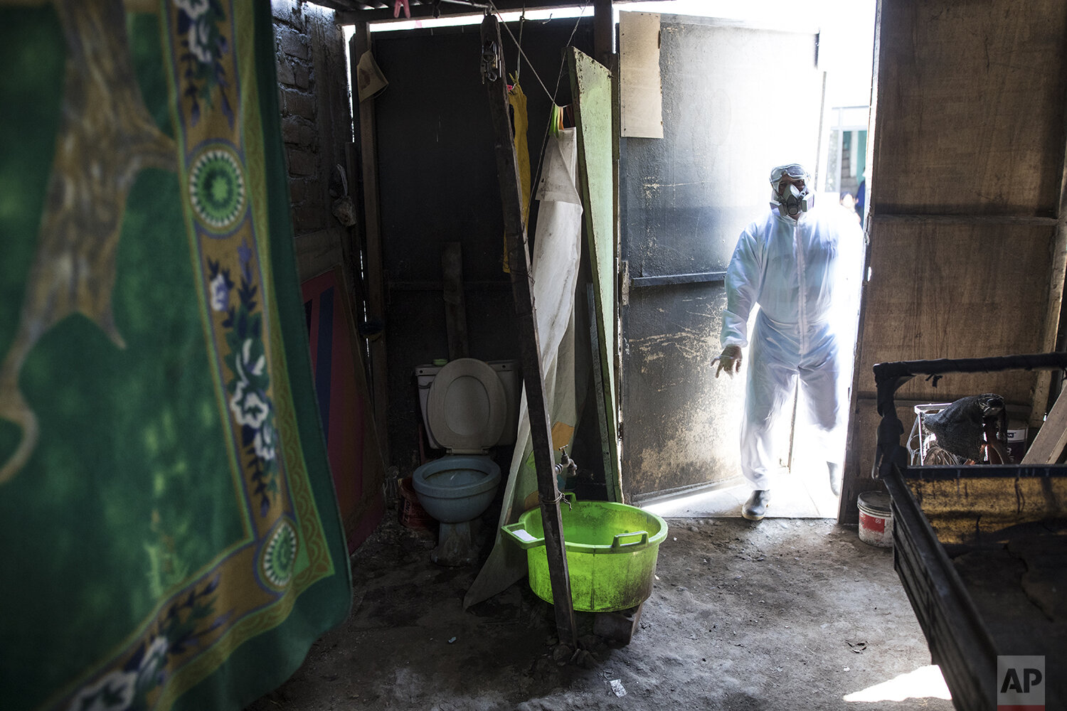  In this May 14, 2020 photo, funeral worker Alexander Carballo, 40, from Venezuela, enters a house of an allegedly victim of Coronavirus to pick up the corpse and carry it to the crematory, in  Lima, Peru. (AP Photo/Rodrigo Abd) 