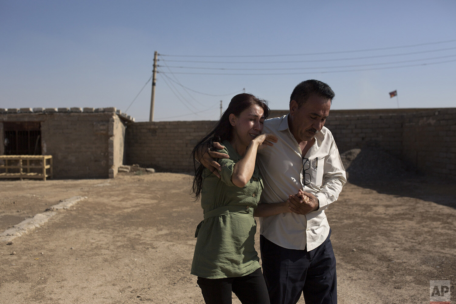  In this Aug. 31, 2019 photo, Layla Taloo is overcome with grief as her brother, Khalid, leads her away from the compound where she last saw her husband in 2014 after the family was captured by Islamic State militants in Tal Afar, Iraq. Her family wa