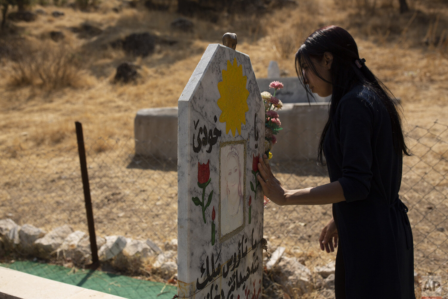  In this Sept. 13, 2019, photo, Layla Taloo visits the grave of a Yazidi woman who took her own life after she was captured by Islamic State militants in Mosul, buried on a hill overlooking the Lalish shrine in northern Iraq.              Some 3,500 