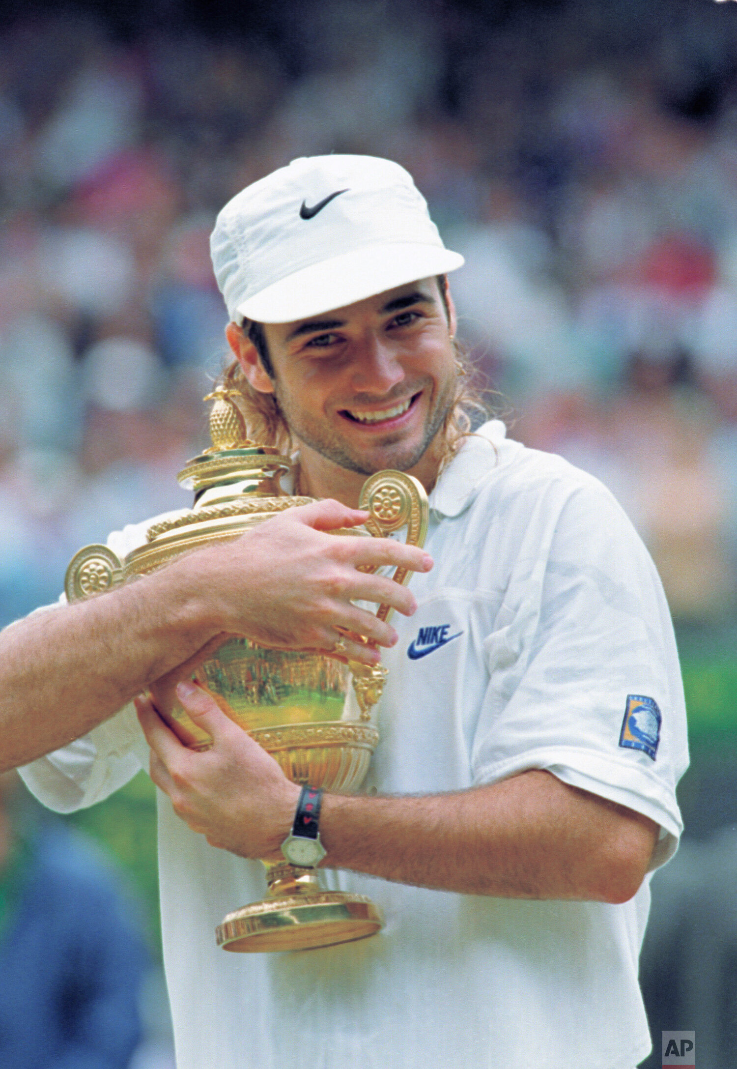  Andre Agassi hugs his trophy after defeating Goran Ivanisevic to win the men's singles final on Centre Court at Wimbledon, Sunday, July 5, 1992. Agassi won 6-7 (8-10), 6-4, 6-4, 1-6, 6-4 to capture his first Grand Slam title. (AP Photo/ Denis Paquin