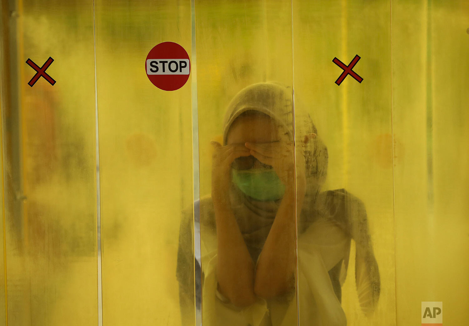  A woman reacts as she is sprayed with disinfectant inside a chamber as a precaution against the new coronavirus outbreak before entering a shopping mall in Jakarta, Indonesia, Tuesday, June 9, 2020.  (AP Photo/Dita Alangkara) 