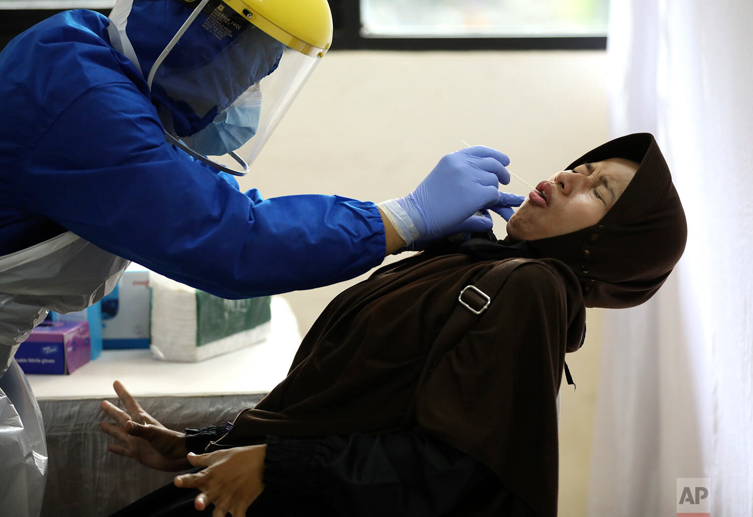  A woman reacts as she has her nasal swab sample collected by a health worker during a mass test for the new coronavirus at the local district office in Tanah Abang in Jakarta, Indonesia, Sunday, June 21, 2020. (AP Photo/Dita Alangkara) 
