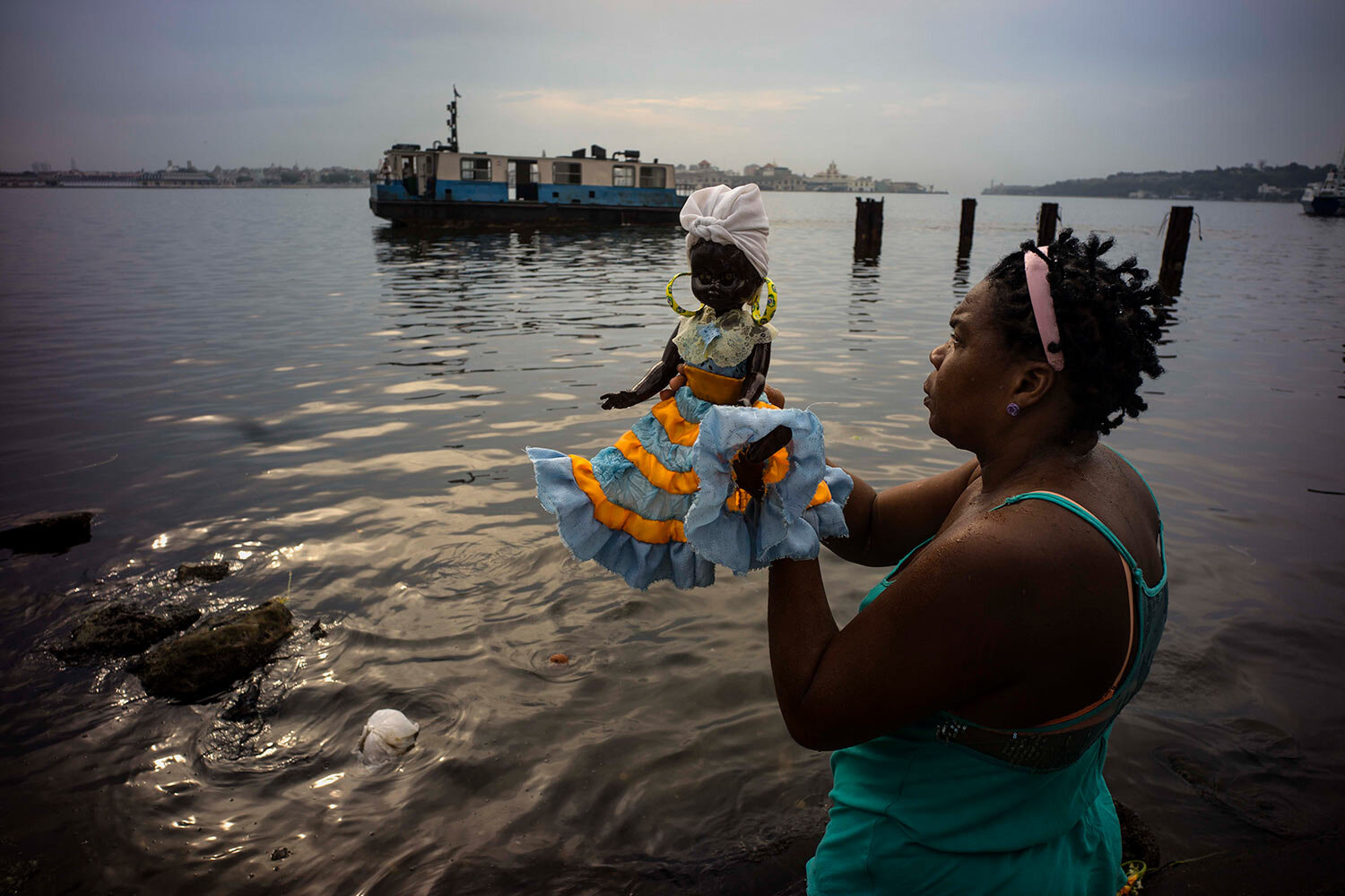  A woman with a doll representing the Virgin of Regla prays at the seaside before a procession in honor of the Virgin in the town of Regla, across the bay from Havana, Cuba, Monday, Sept. 7, 2015. (AP Photo/Ramon Espinosa) 