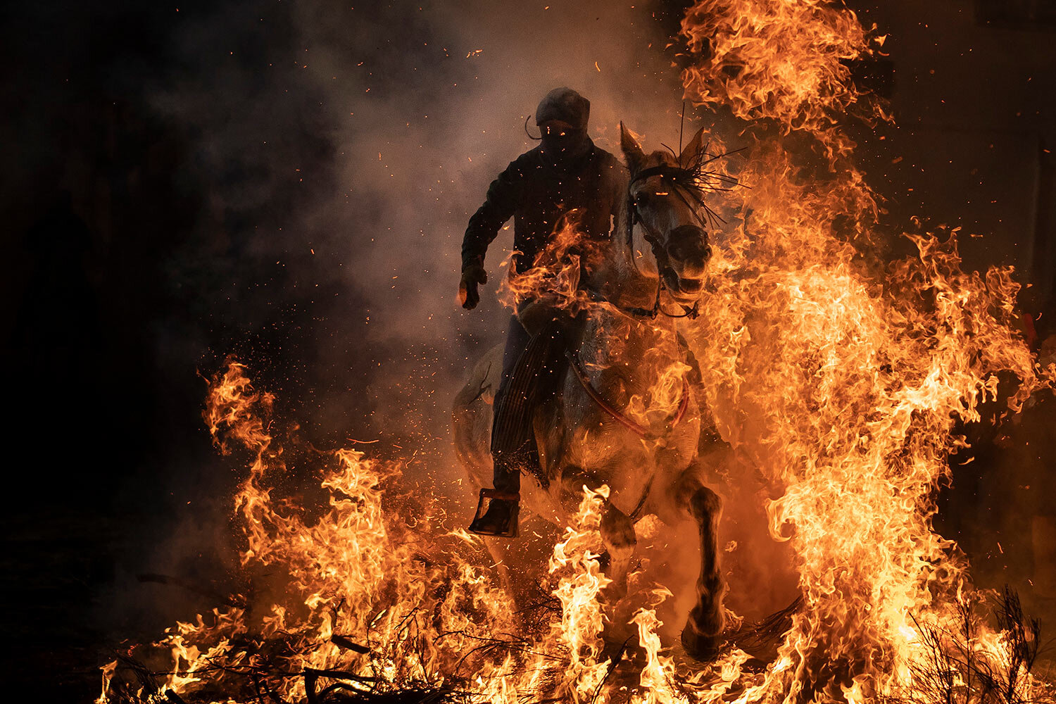  A man rides a horse through a bonfire as part of a ritual in honor of Saint Anthony the Abbot, the patron saint of domestic animals, in San Bartolome de Pinares, Spain, Wednesday, Jan. 16, 2019. On the eve of Saint Anthony's Day, dozens ride their h