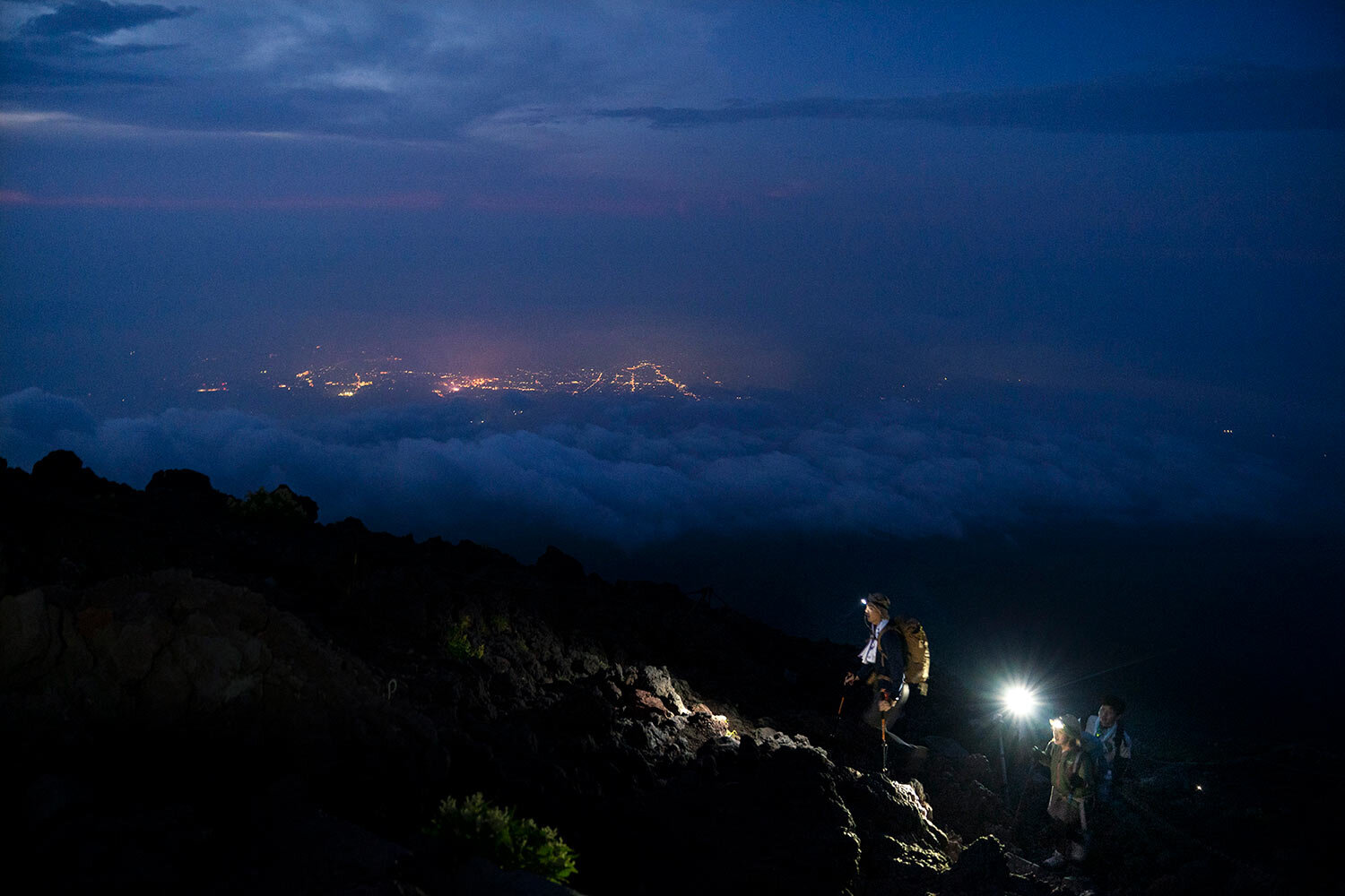  Climbers make their way along the Yoshida trail toward the summit of Mount Fuji as the glow from the town's lights are visible through clouds Friday, Aug. 2, 2019, in Japan. (AP Photo/Jae C. Hong) 
