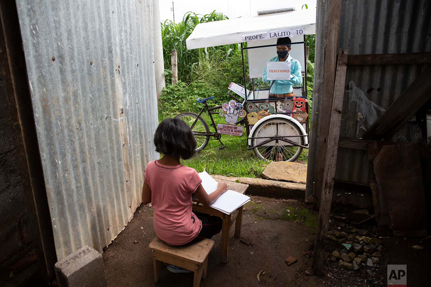  Gerardo Ixcoy teaches 12-year-old student Paola Ximena Conoz about fractions from his mobile classroom, parked just outside the door to her home in Santa Cruz del Quiche, Guatemala, Wednesday, July 15, 2020. Each day the 27-year-old sets out pedalin
