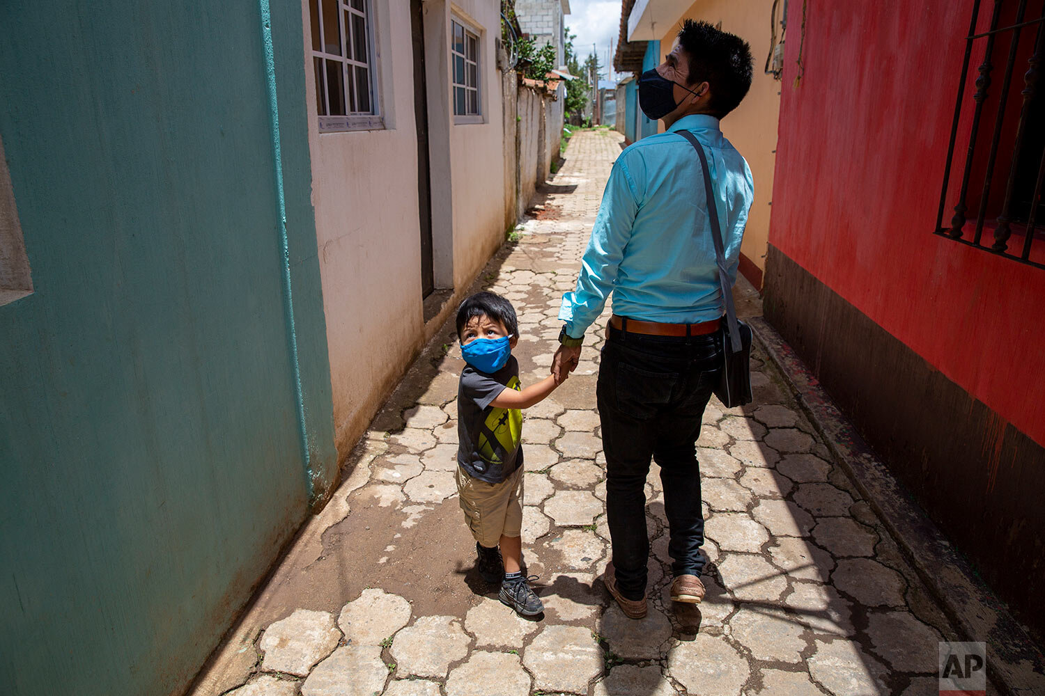  Teacher Gerardo Ixcoy and his three-year-old son Dylan greet a neighbor as Ixcoy arrives home after a day of giving individual instruction to his sixth-grade students, in Santa Cruz del Quiche, Guatemala, Wednesday, July 15, 2020. By afternoon Ixcoy