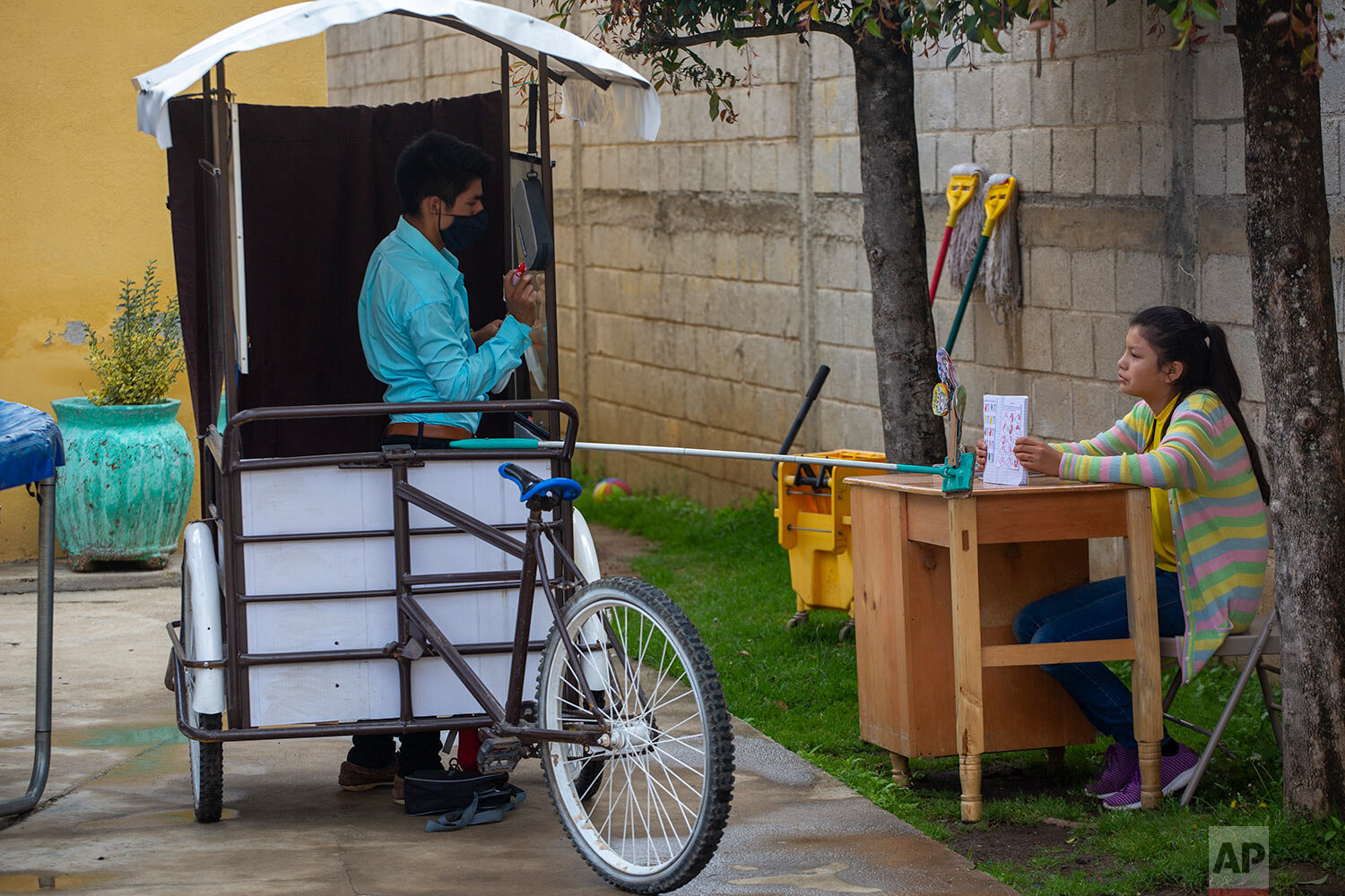  Gerardo Ixcoy teaches fractions to 14-year-old Brenda Morales, from his secondhand adult tricycle that he converted into a mobile classroom, in Santa Cruz del Quiche, Guatemala, Wednesday, July 15, 2020. The 27-year-old teacher deploys a sponge mop 