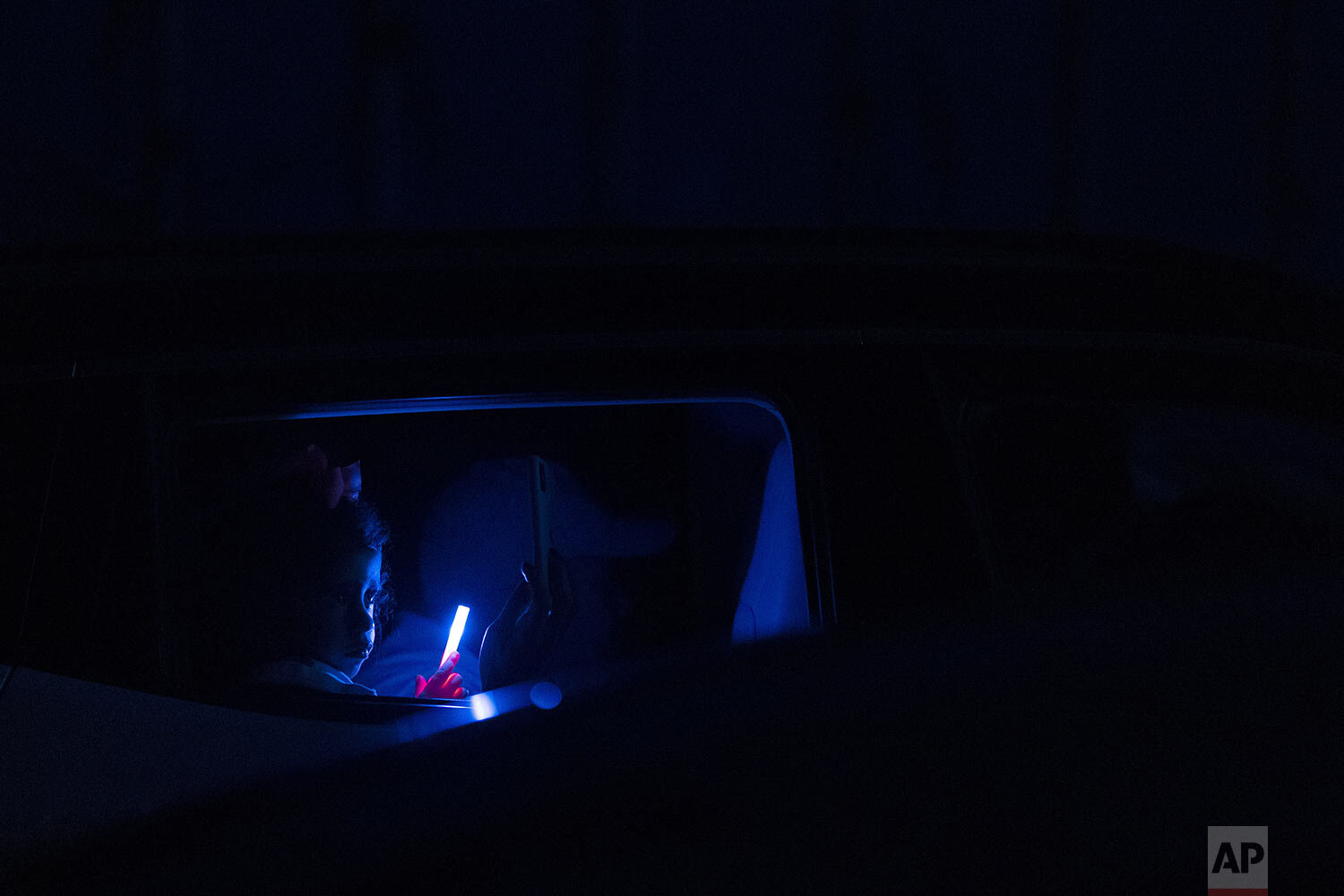  A girl holds a light stick inside her car as she watches the Estoril Circus drive-in show in Itaguai, in greater Rio de Janeiro, Brazil, July 18, 2020. (AP Photo/Leo Correa) 