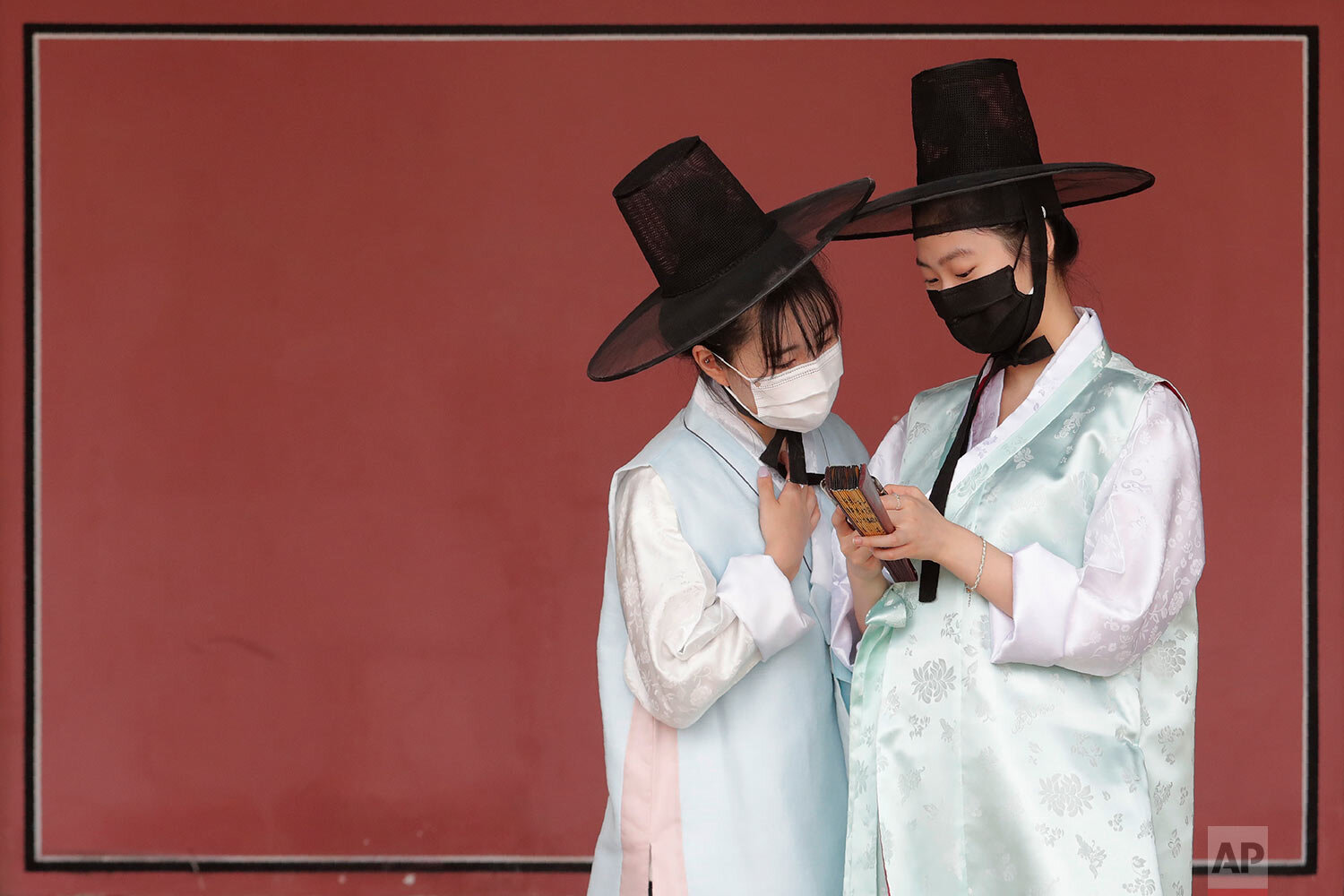  Women wearing face masks to help protect against the spread of the new coronavirus watch a mobile phone at the Gyeongbok Palace, one of South Korea's well-known landmarks, in Seoul, South Korea, Saturday, July 25, 2020.  (AP Photo/Ahn Young-joon) 