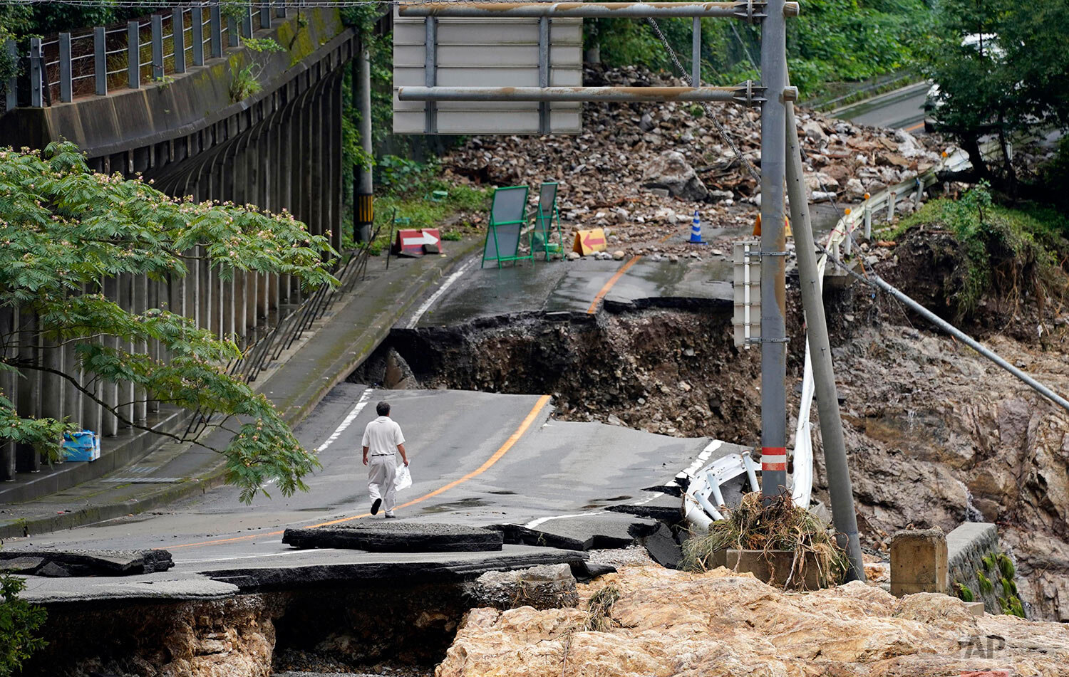  A man walks on heavily damaged road following a heavy rain in Kumamura, Kumamoto prefecture, southern Japan Monday, July 6, 2020. (Koji Harada/Kyodo News via AP) 