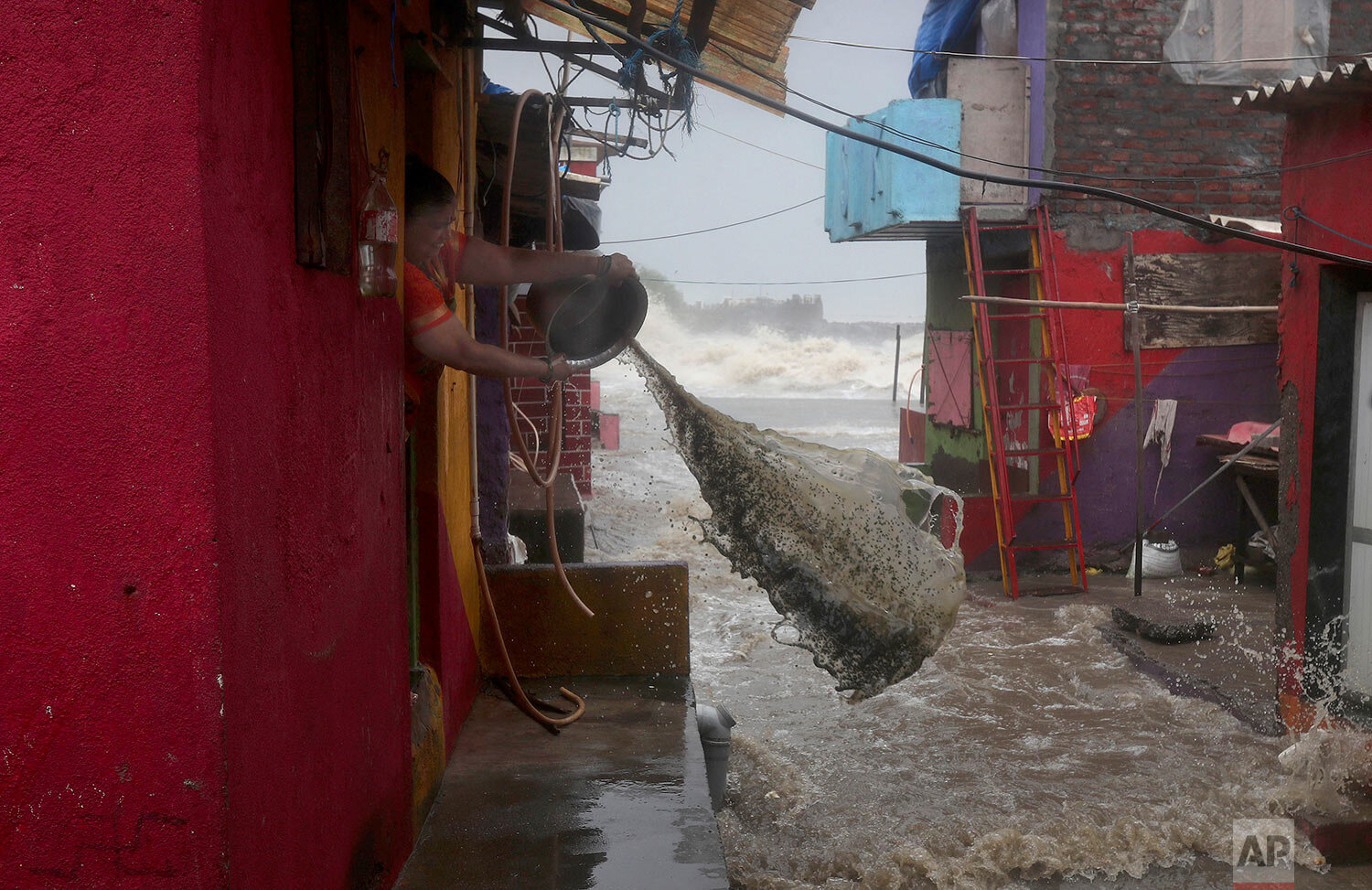  A woman tries to remove high tide water from her house at a shanty area on the Arabian Sea coast in Mumbai, India, Monday, July 6, 2020.  (AP Photo/Rafiq Maqbool) 