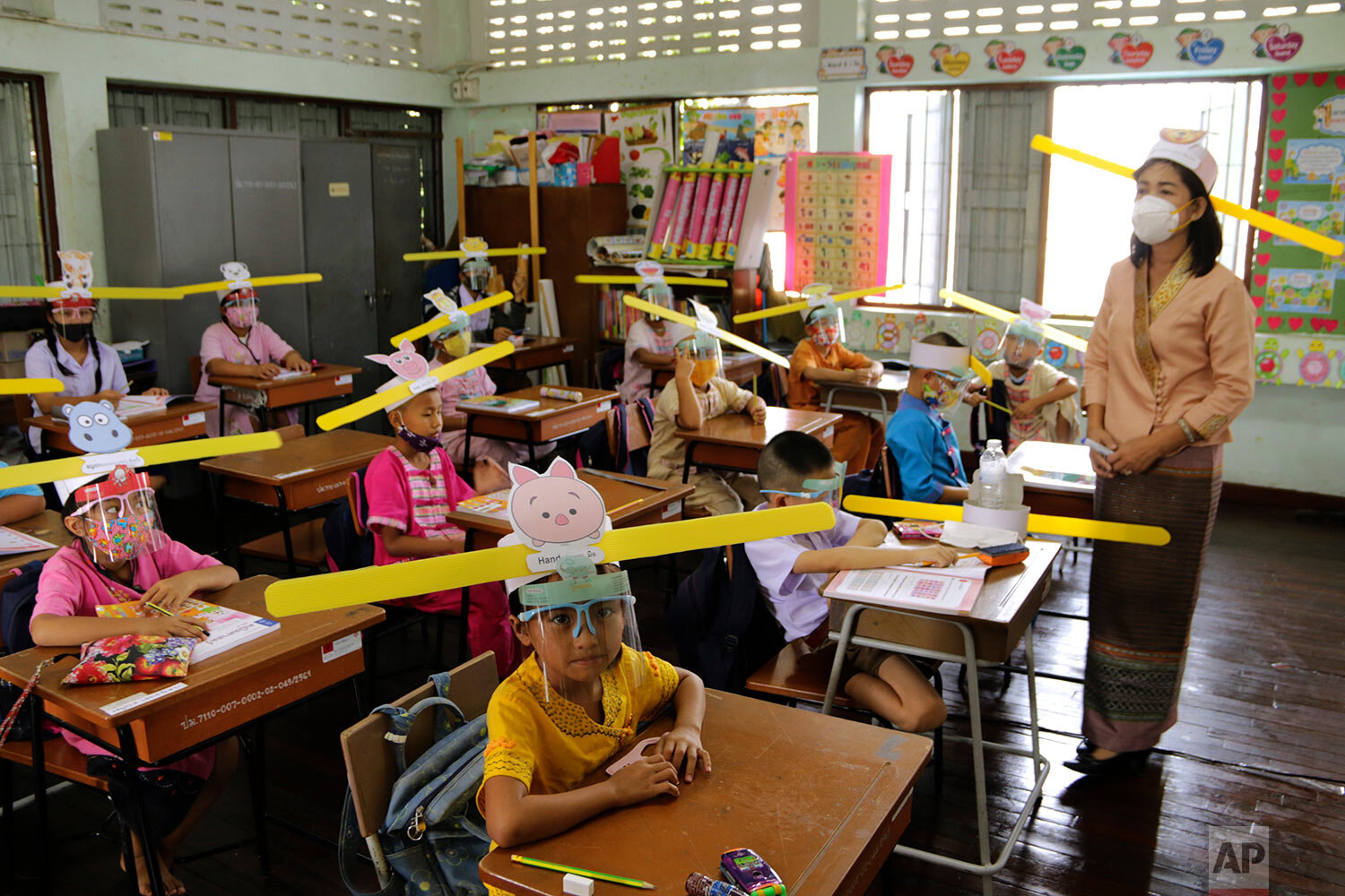  A teacher and students wearing hats designed for space keeper, practice social distancing to help curb the spread of the coronavirus at Ban Pa Muad School in Chiang Mai, north of Thailand, Friday, July 3, 2020. (AP Photo/ Wichai Taprieu) 
