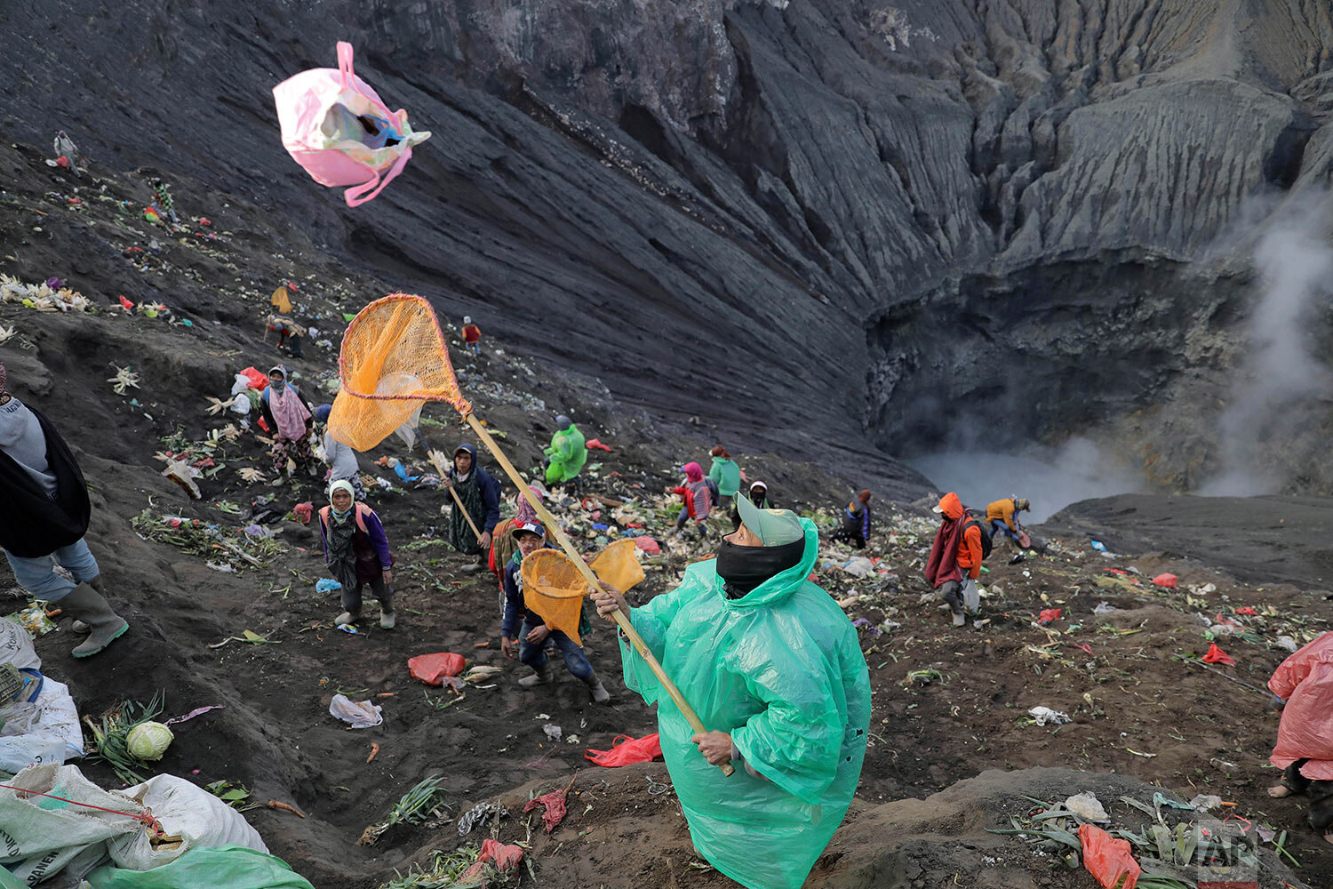  A villager uses his net to catch offerings thrown into the crater of Mount Bromo by Hindu devotees during Yadnya Kasada festival in Probolinggo, East Java, Indonesia, Tuesday, July 7, 2020.  (AP Photo/Trisnadi) 