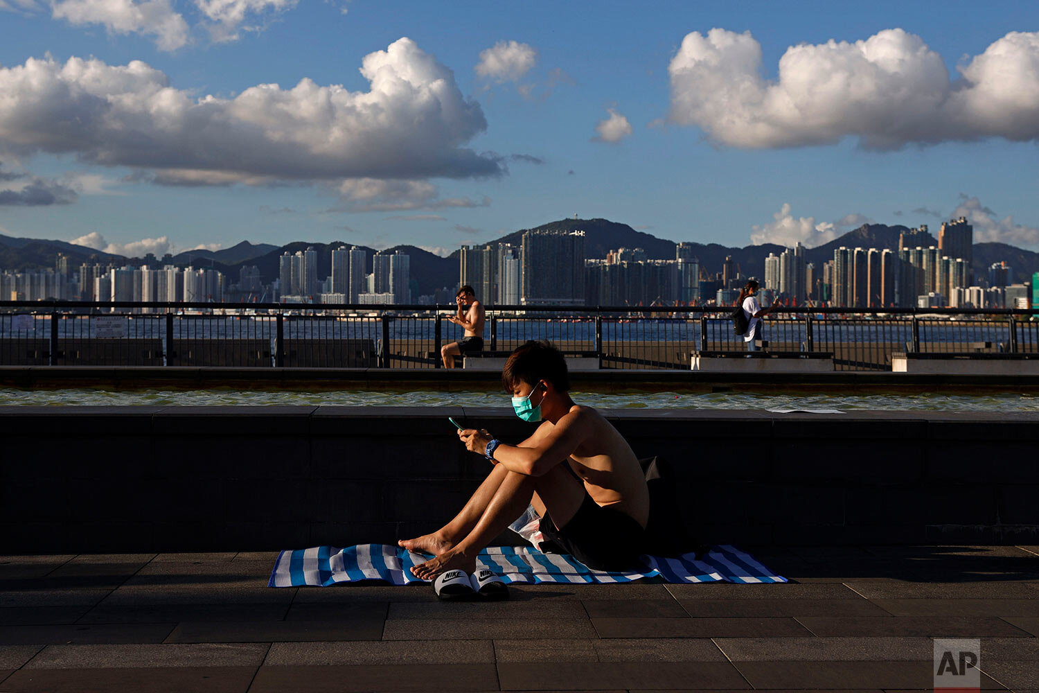  A man wearing a face mask to protect against the new coronavirus sits in the sun at a park in Hong Kong, Wednesday, July 22, 2020. (AP Photo/Kin Cheung) 