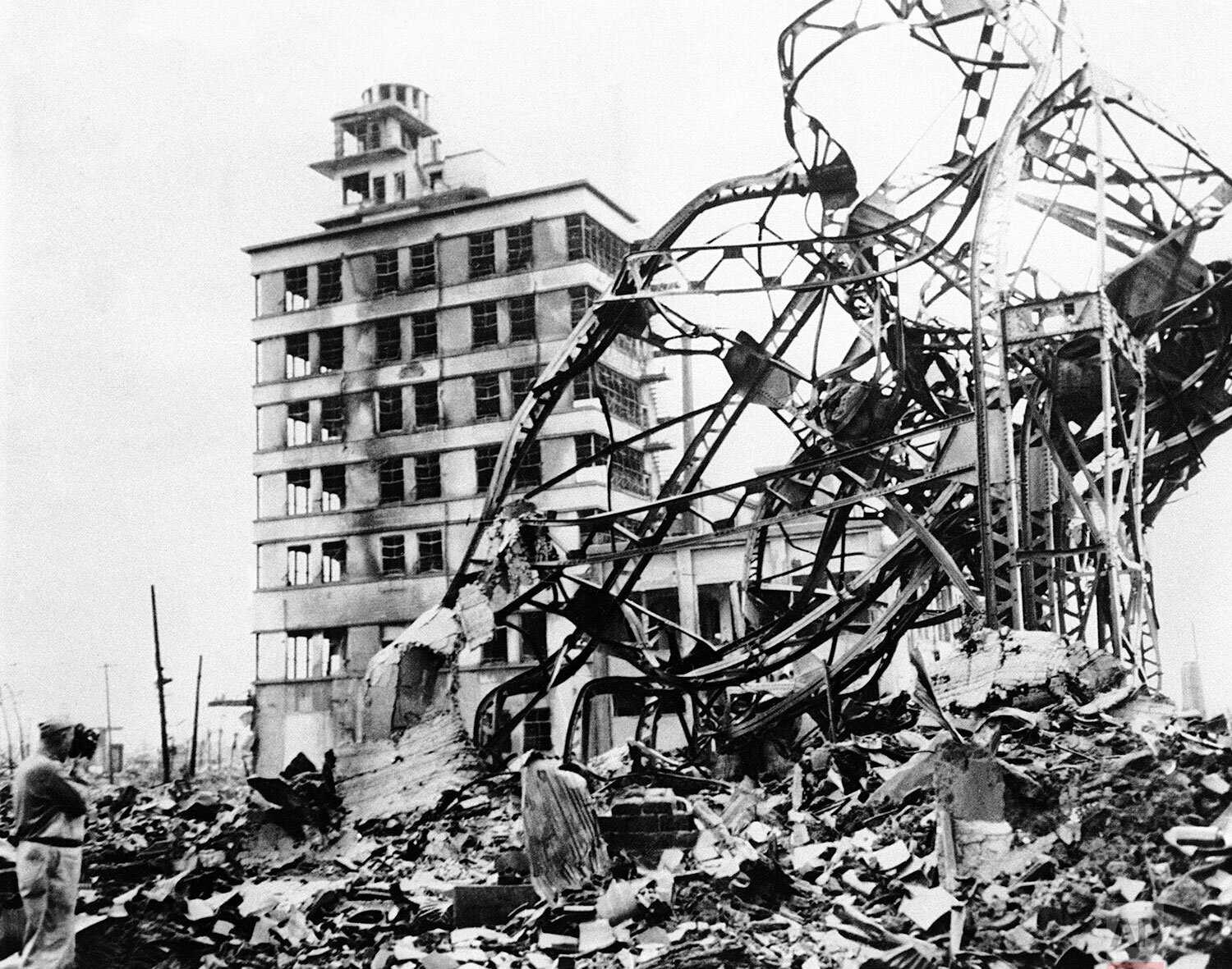  A twisted mass of steel, marks the site of a large building in the industrial centre of atomized Hiroshima, Japan, on Sept. 13, 1945, directly behind, in grim contrast, a partly demolished building towers up, amid acres of gutted and fire blackened 