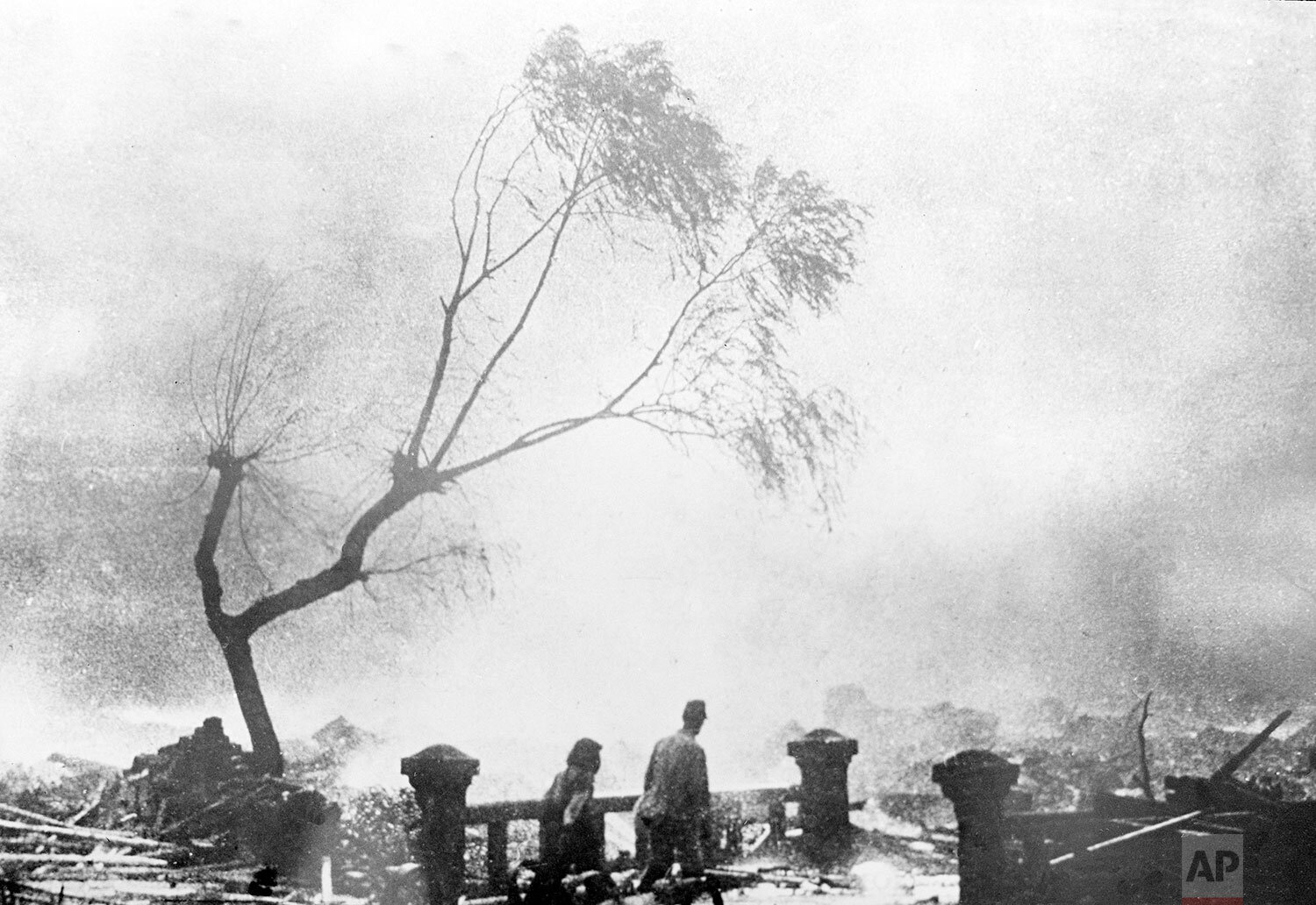  Survivors of the atomic bomb attack of Nagasaki walk through the destruction as fire rages in the background, Aug. 9, 1945. (AP Photo) 