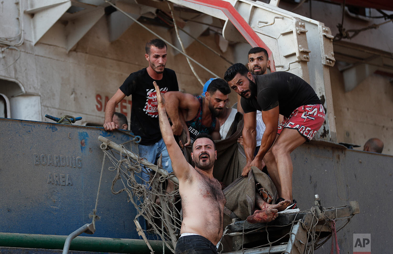  Civilians help to evacuate an injured sailor from a ship which was docked near the explosion scene that hit the seaport of Beirut, Lebanon, Tuesday, Aug. 4, 2020. (AP Photo/Hussein Malla) 