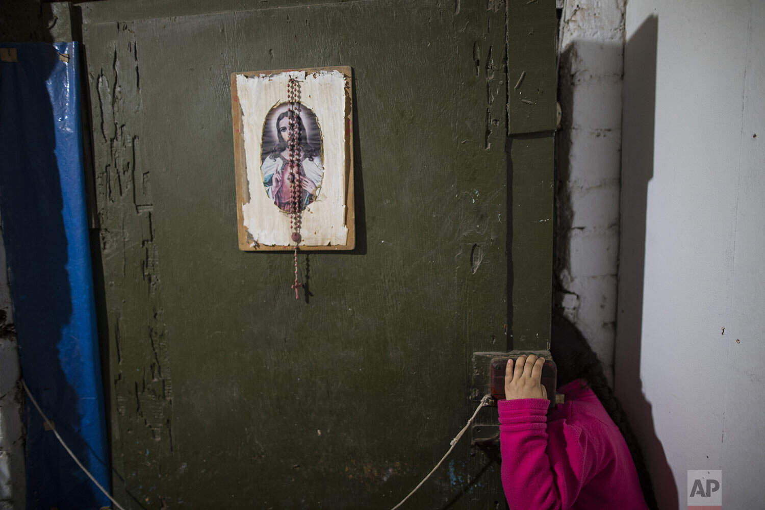 A child looks out her front door while Brother Ronald Marin pays a visit to pray with family members of COVID-19 victims, in Comas, on the outskirts of Lima, Peru, Thursday, July 23, 2020. (AP Photo/Rodrigo Abd) 