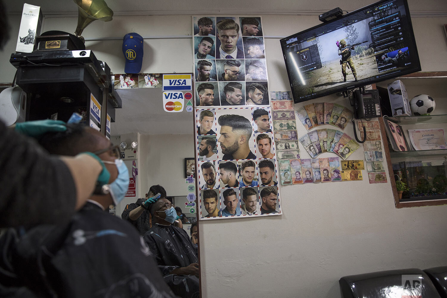  Brother Ronald Marin entertains himself with a video game while his friend Jimmy, a barber, trims his hair in Los Olivos, on the outskirts of Lima, Peru, Thursday, July 23, 2020. (AP Photo/Rodrigo Abd) 