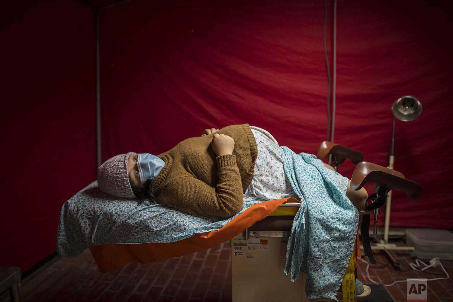  Olinda Tafur, 20, lies on an examination table as she waits to be seen by obstetrician Dr. Osvaldo Sierra inside a tent set up in the emergency area of the National Perinatal and Maternal Institute to receive women in labor who are infected with COV