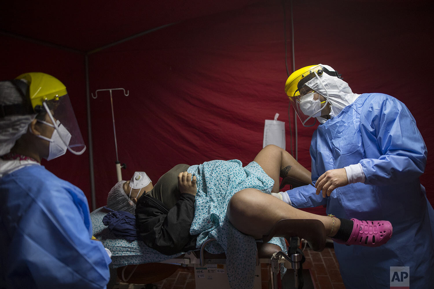  Dr. Osvaldo Sierra gauges the cervical dilation of Maria Novella inside a red tent set up to receive expectant mothers who have tested positive for the new coronavirus, at the National Maternal Perinatal Institute, in Lima, Peru, Thursday, July 9, 2