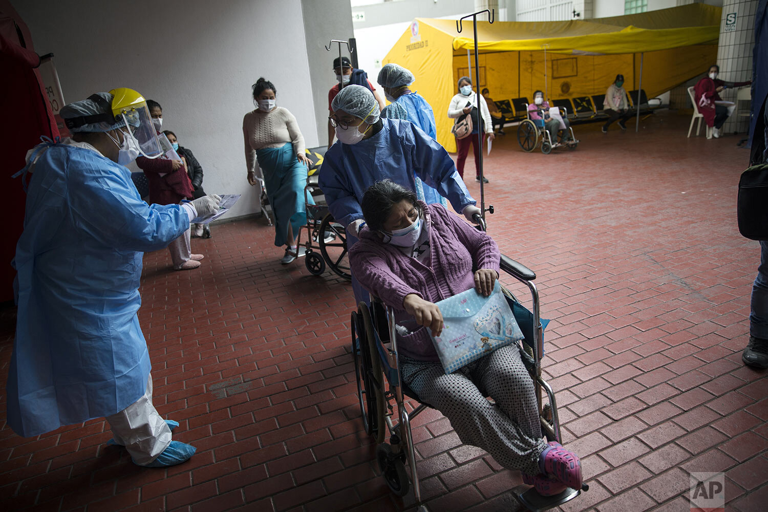  A nurse receives an expectant mother at an entry checkpoint who must be tested for COVID-19 before she can be admitted, outside the emergency entrance of the National Maternal Perinatal Institute, in Lima, Peru, Wednesday, July 29, 2020. (AP Photo/R