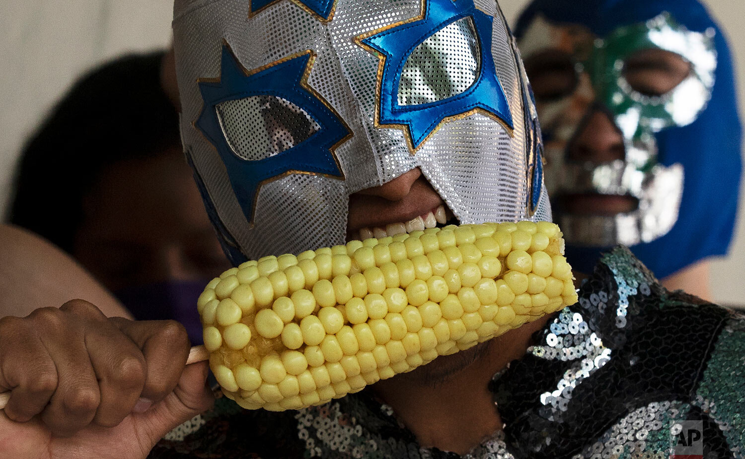  A Lucha Libre wrestler eats corn as he takes part in a health campaign promoting the use of masks amid the COVID-19 pandemic at the market in Xochimilco on the outskirts of Mexico City, Wednesday, Aug. 19, 2020. (AP Photo/Marco Ugarte) 