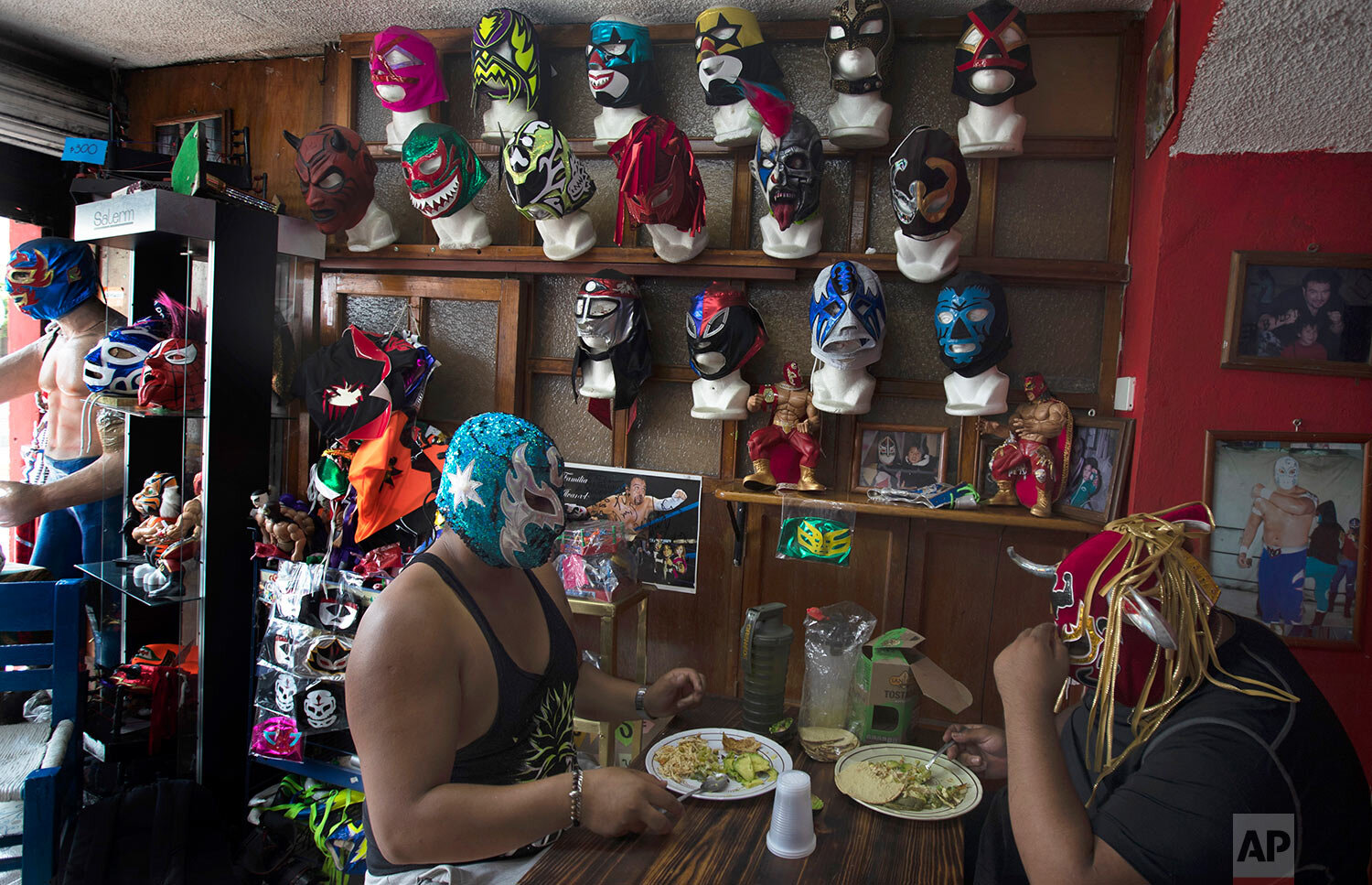  Lucha Libre brothers "Ciclonico," or Cyclone, left, and Mister Jerry, eat at their restaurant that also sells fighter masks in Xochimilco on the outskirts of Mexico City, Wednesday, Aug. 19, 2020. (AP Photo/Marco Ugarte) 