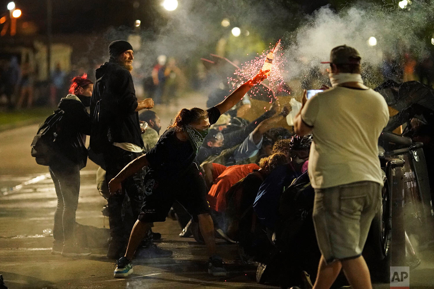  A protester tosses an object toward police during clashes outside the Kenosha County Courthouse late Tuesday, Aug. 25, 2020, in Kenosha, Wis., on third night of unrest following the shooting of a Black man, Jacob Blake, whose attorney said he was pa