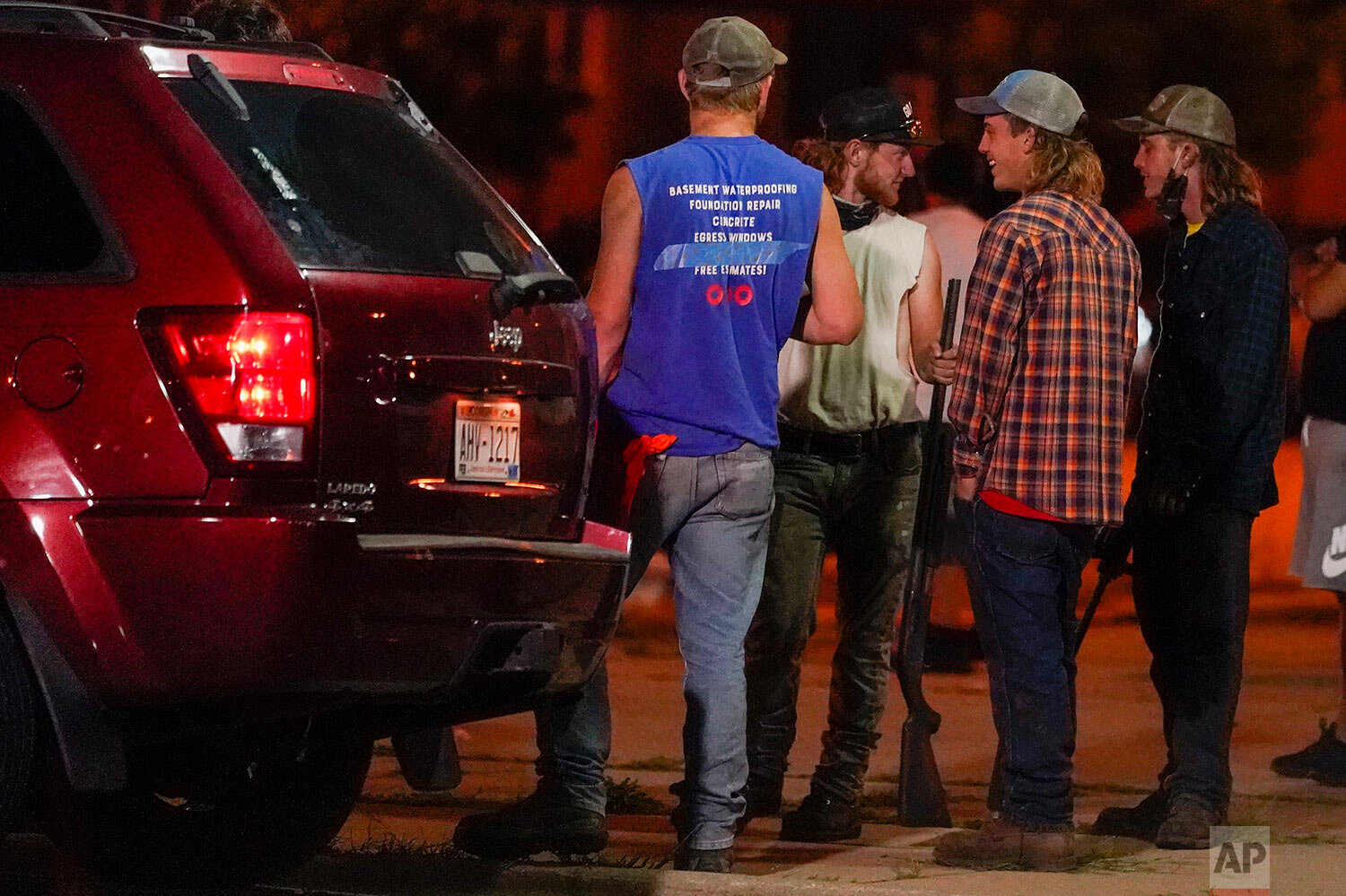  A group holds rifles as they watch protesters on the street Tuesday, Aug. 25, 2020, in Kenosha, Wis. (AP Photo/Morry Gash) 