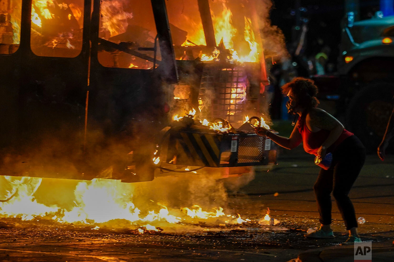  A protester lights a cigarette on a garbage truck that was set on fire during protests late Monday, Aug. 24, 2020, in Kenosha, Wis., sparked by the shooting of Jacob Blake by a Kenosha Police officer a day earlier. (AP Photo/Morry Gash) 
