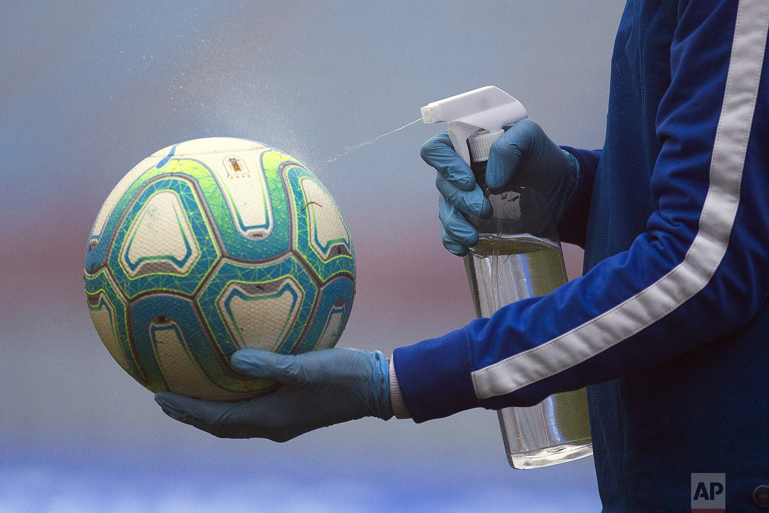  A ball catcher wearing gloves disinfects a soccer ball at a championship match between Nacional and Penarol in Montevideo, Uruguay, Aug. 9, 2020. The two greats of Uruguayan soccer tied 1-1 at the return of the local league, after a five month pause