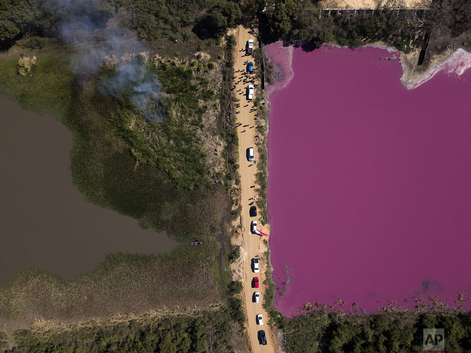  Cars are parked over Cerro Lagoon as the drivers protest the Waltrading S.A. tannery company for dumping untreated waste into the lagoon turning the water purple and emitting a foul odor in Limpio, Paraguay, Aug. 22, 2020. (AP Photo/Jorge Saenz) 