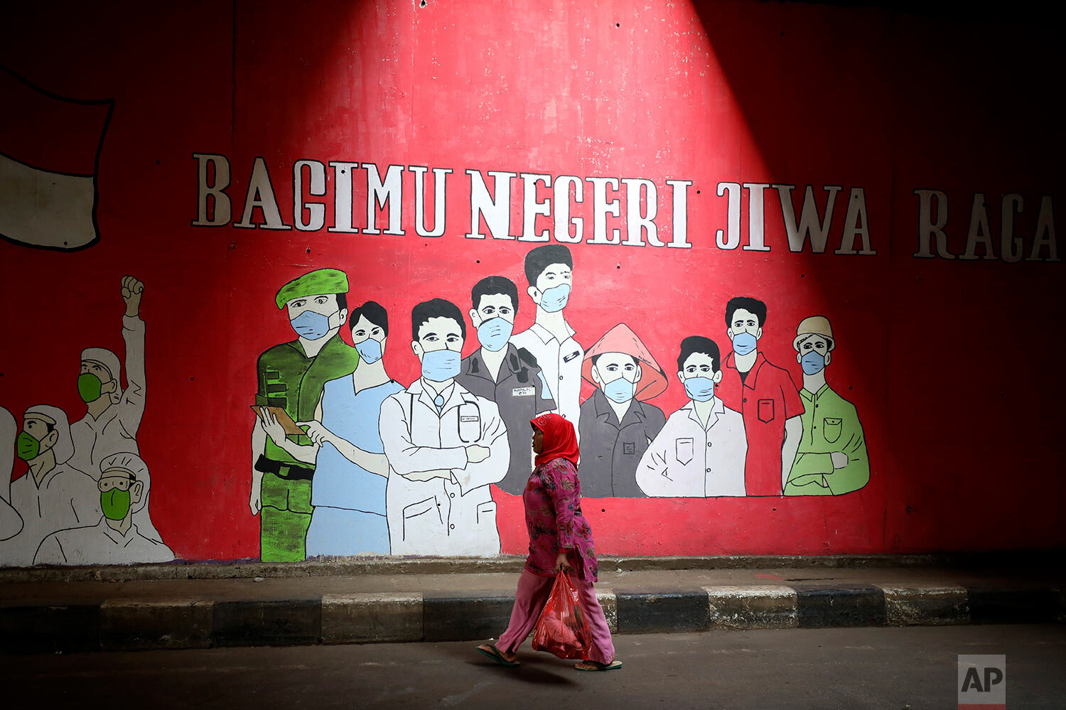  A woman walks past a coronavirus-themed mural honoring health and other essential workers, in Jakarta, Indonesia, Wednesday, Aug. 26, 2020. Writings on the mural read: "Our body and soul for the country." (AP Photo/Dita Alangkara) 