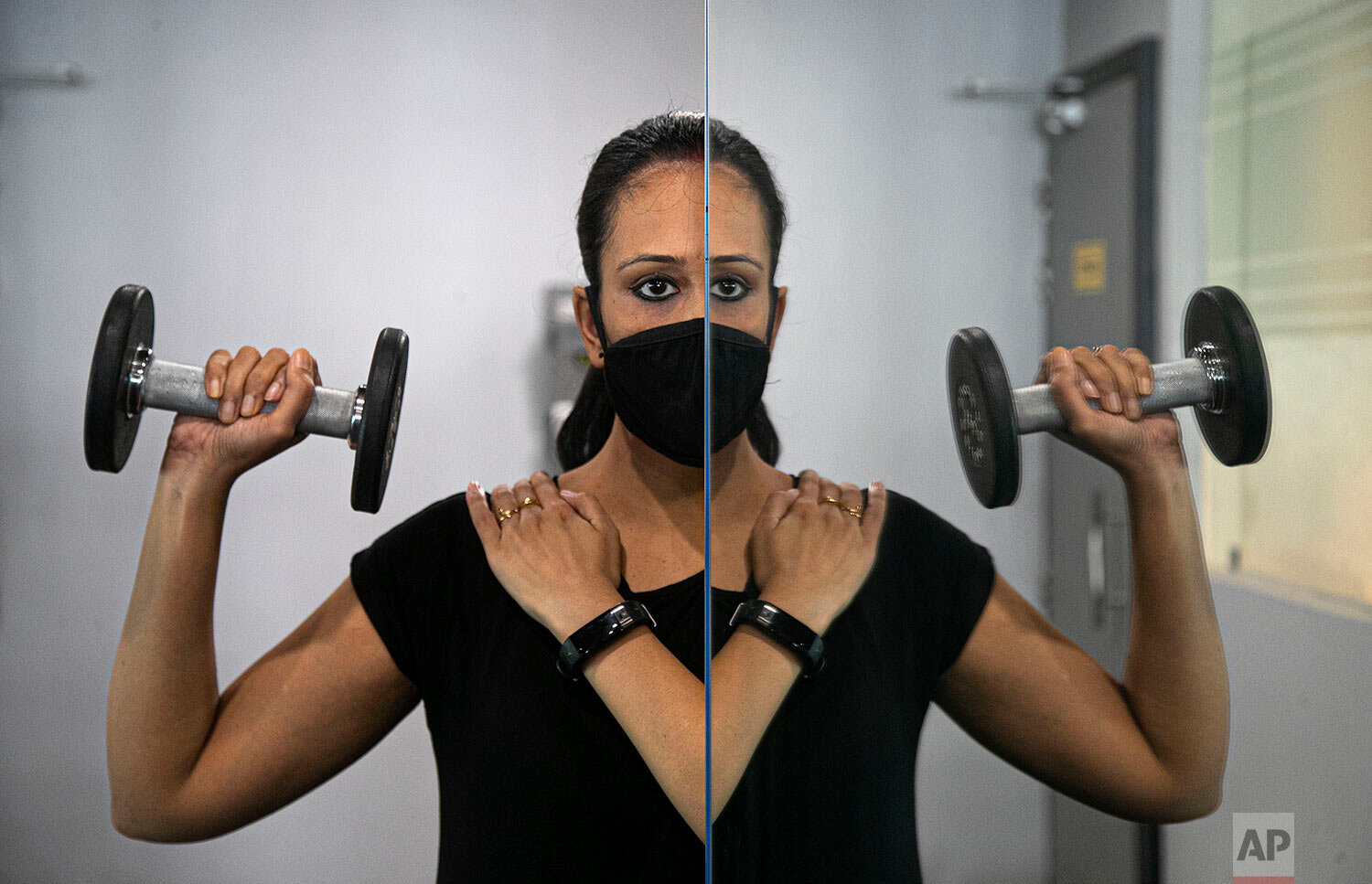  An Indian woman working out is reflected on a mirror of a gym that reopened after lockdown in Gauhati, India, Wednesday, Aug. 5, 2020. (AP Photo/Anupam Nath) 