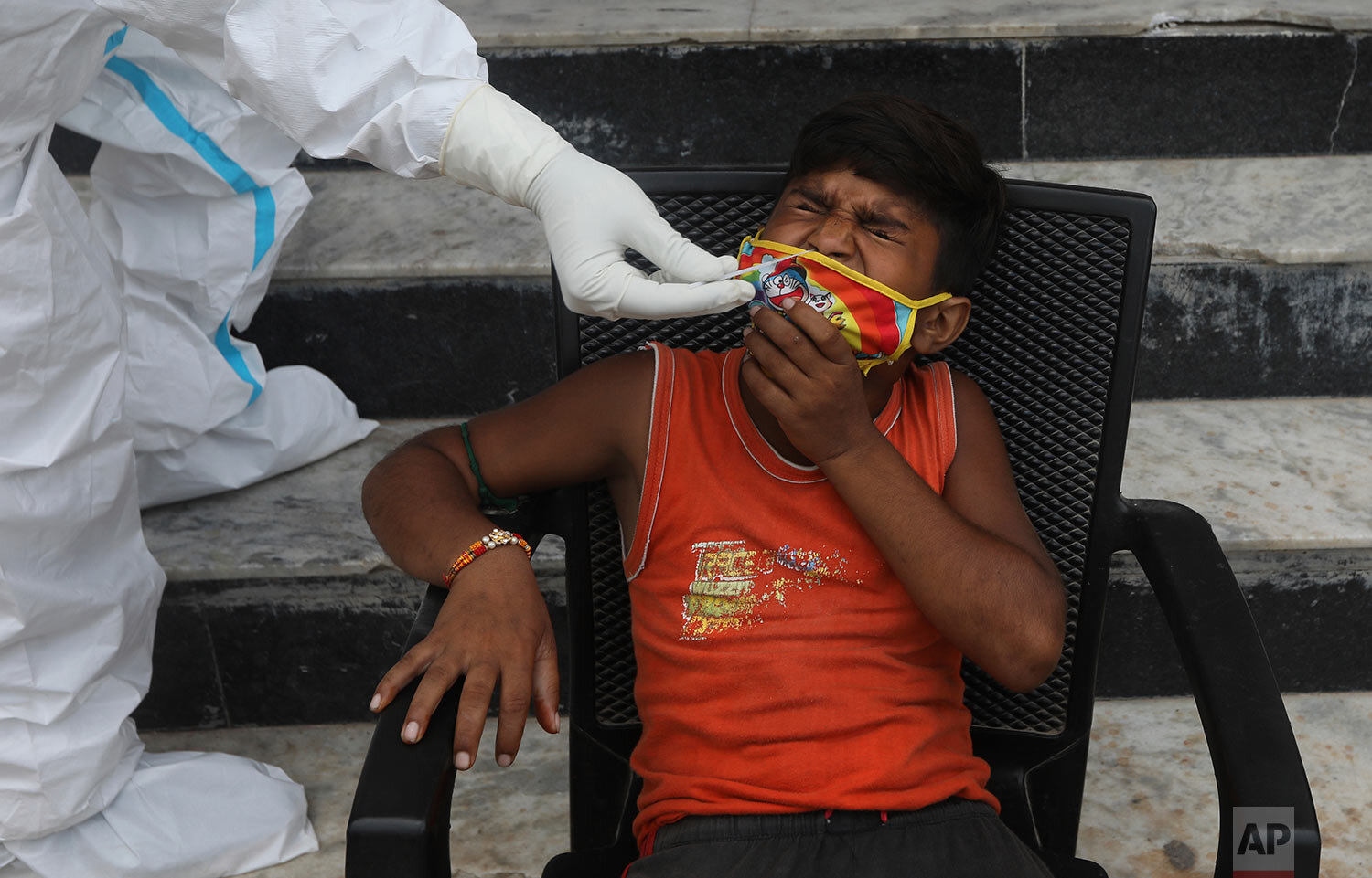  A child grimaces as a health worker takes a nasal swab sample for COVID- 19 testing through rapid antigen methodology, in New Delhi, India , Friday, Aug. 7, 2020. (AP Photo/Manish Swarup) 