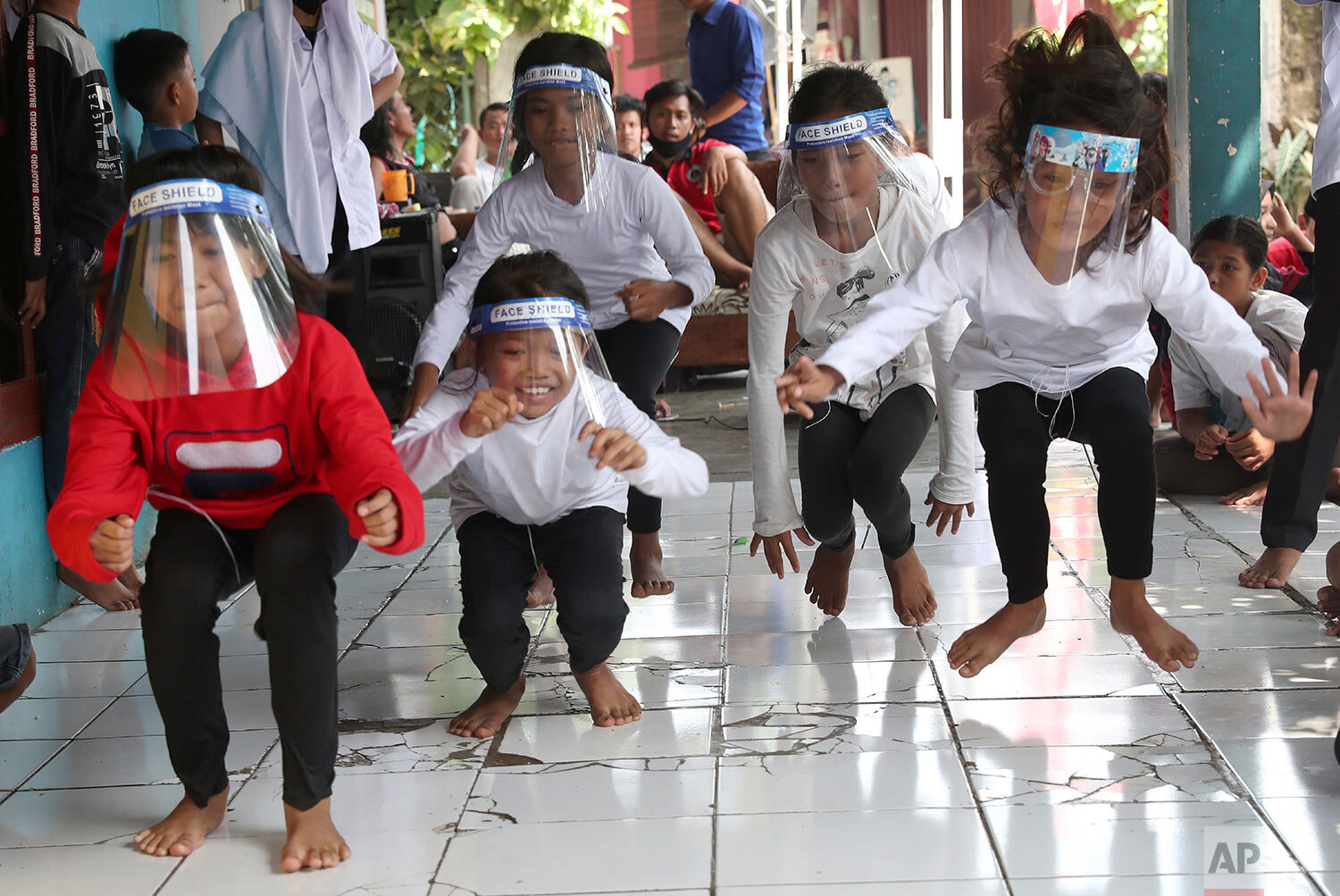  Children wearing face shields as a precaution against the coronavirus take part in a "leap frog" race during a performance held as a part of a celebration of the country's 75th anniversary of independence in Tangerang, Indonesia, Monday, Aug. 17, 20