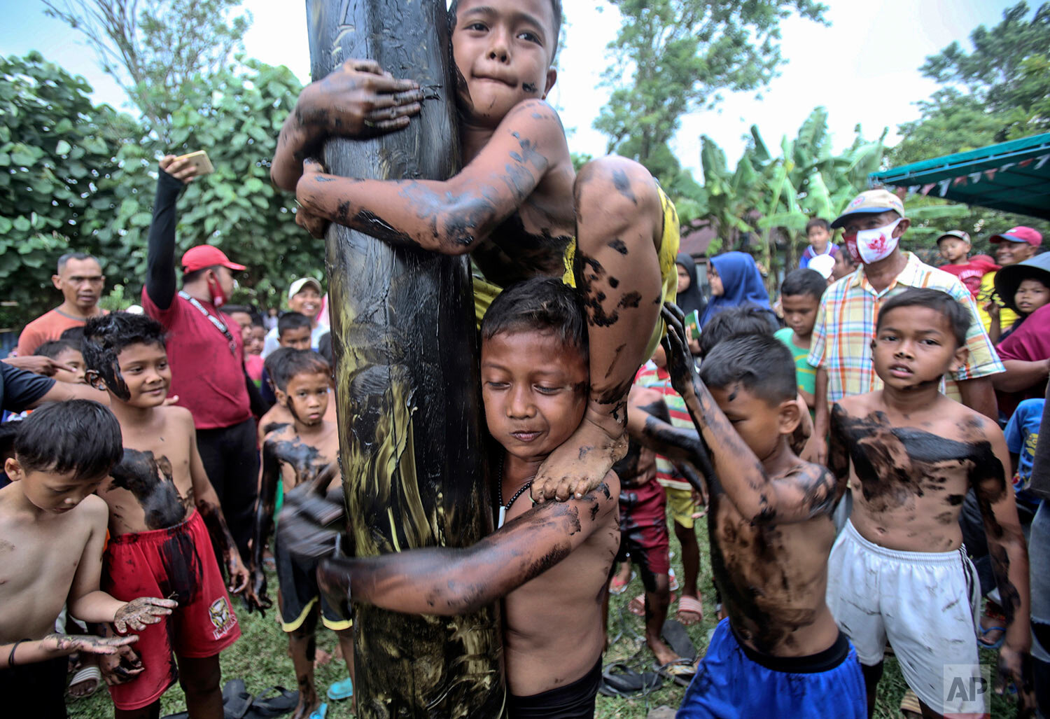  Children take part in a greased-pole climbing competition during the celebration of the 75th anniversary of the country's independence in Medan, North Sumatra, Indonesia, Monday, Aug. 17, 2020. (AP Photo/Binsar Bakkara) 