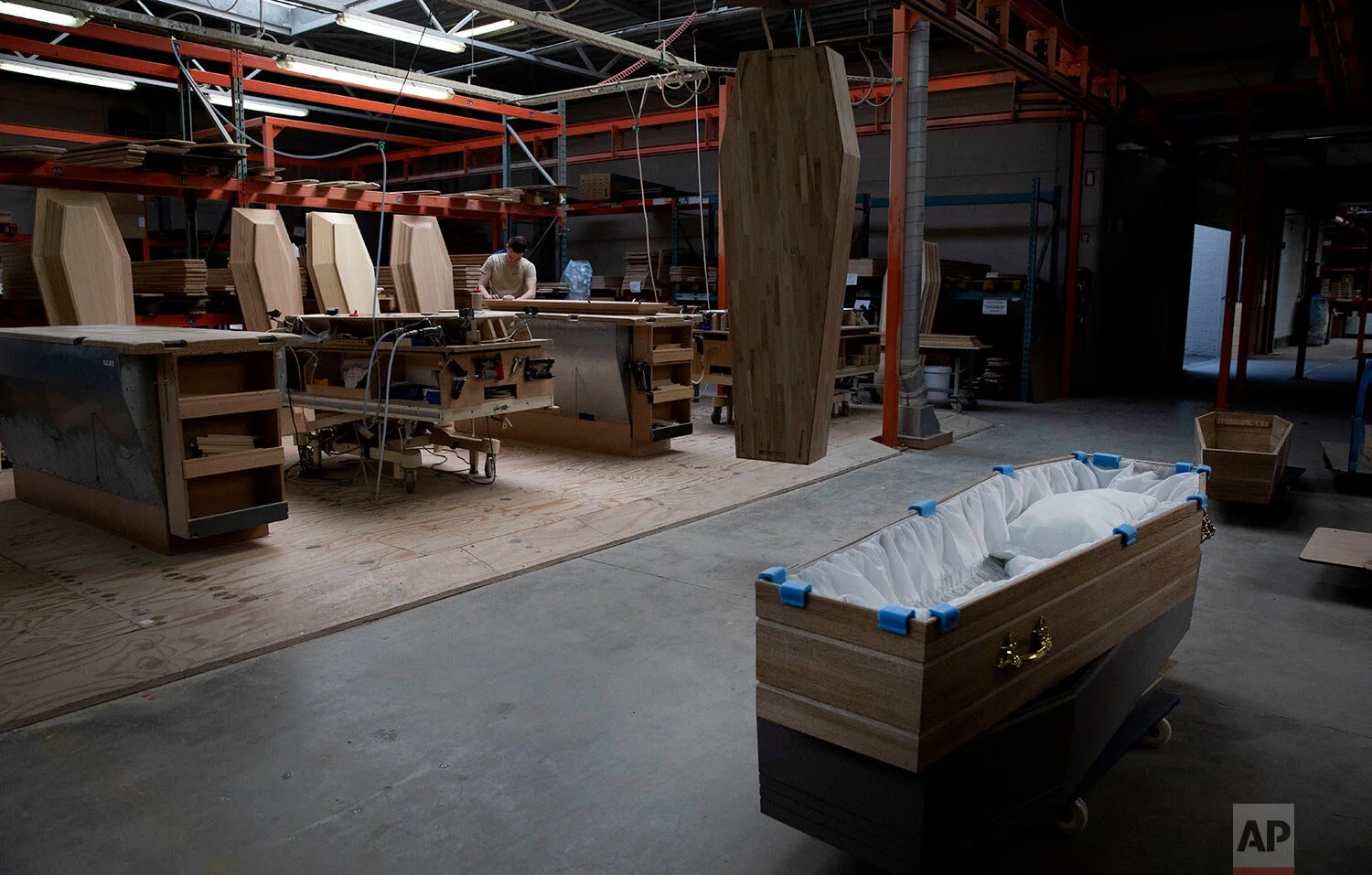 An employee at a woodworking station works on a section of a casket at the production warehouse of Aninco in Peer, Belgium, Thursday, April 9, 2020. Aninco has been in extra production in the last weeks due to an increase in funerals of Covid-19 pat