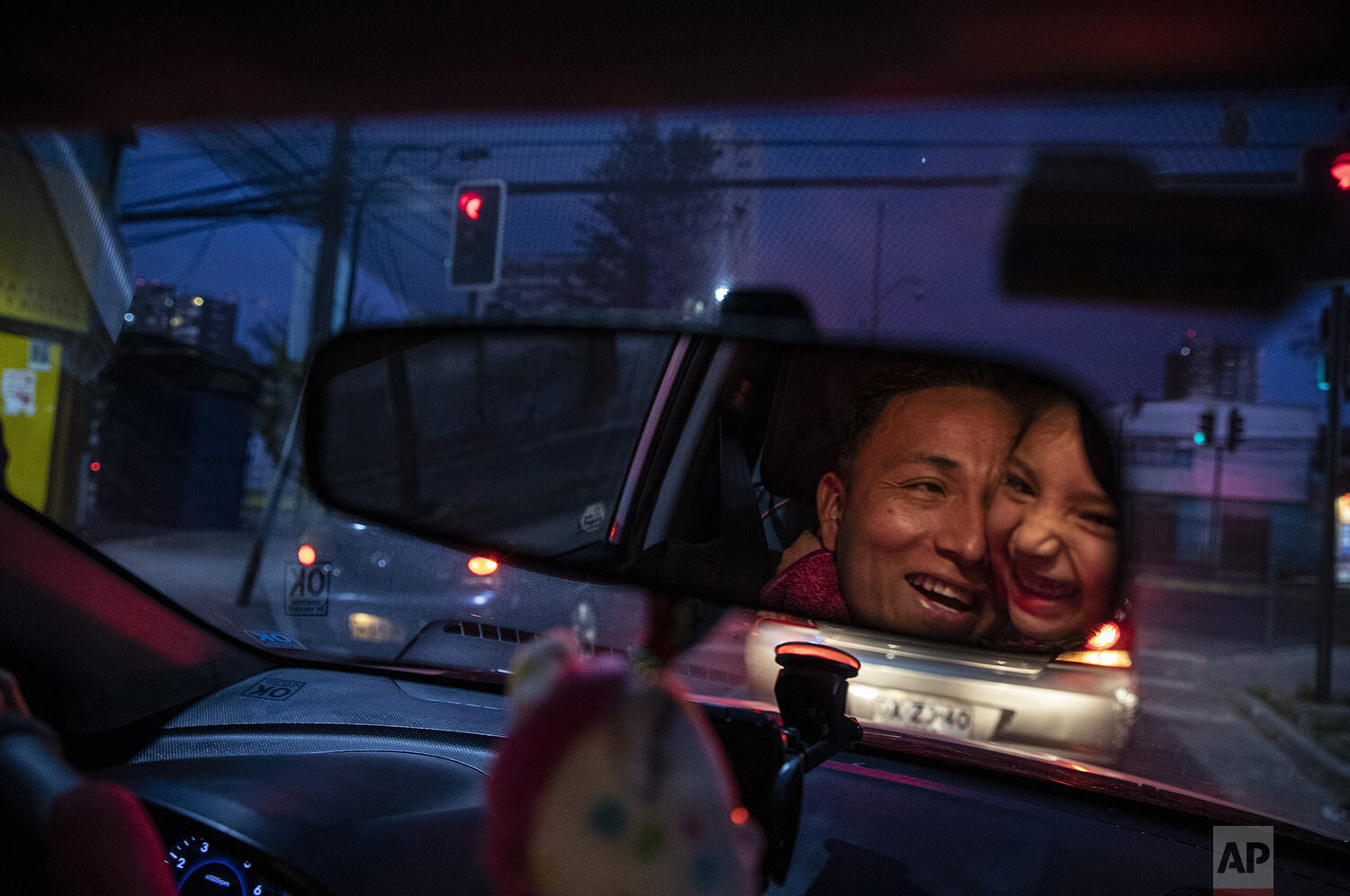  Reflected in the rearview mirror, Jose Collantes gets a hug from daughter Kehity while they're stopped at a red light, as Jose drives his five-year-old home from a playdate in Santiago, Chile, Sept. 6, 2020, three months after they lost his wife, he