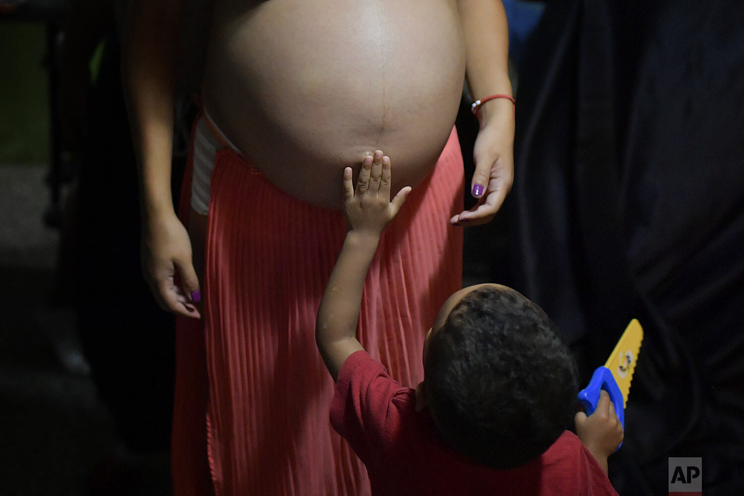  Ada Mendoza's nephew touches her pregnant belly at her parents' apartment where she lives with her partner and seven relatives in the Catia neighborhood of Caracas, Venezuela, Aug. 27, 2020. Mendoza, who must use public transport to get to her prena