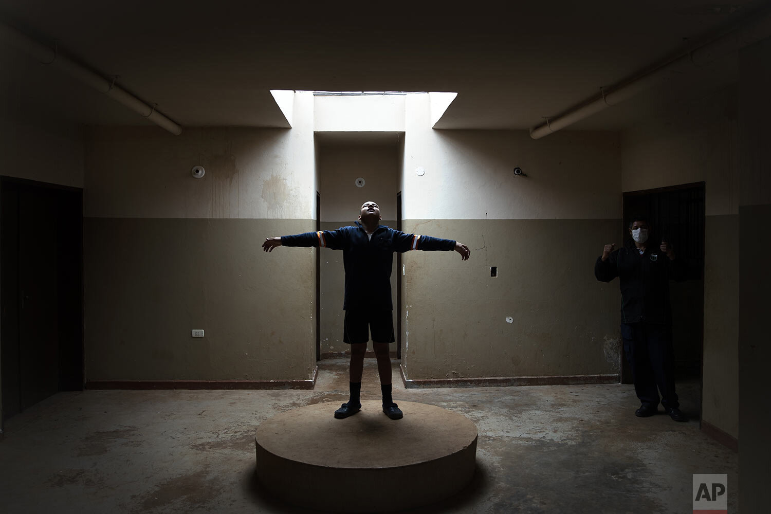  An inmate jokes around where the statue of a saint used to stand, as a guard talks on his radio at the Educational Center of Itagua for juvenile offenders in Itagua, Paraguay, Sept. 14, 2020. Visiting privileges were suspended at the start of the ne