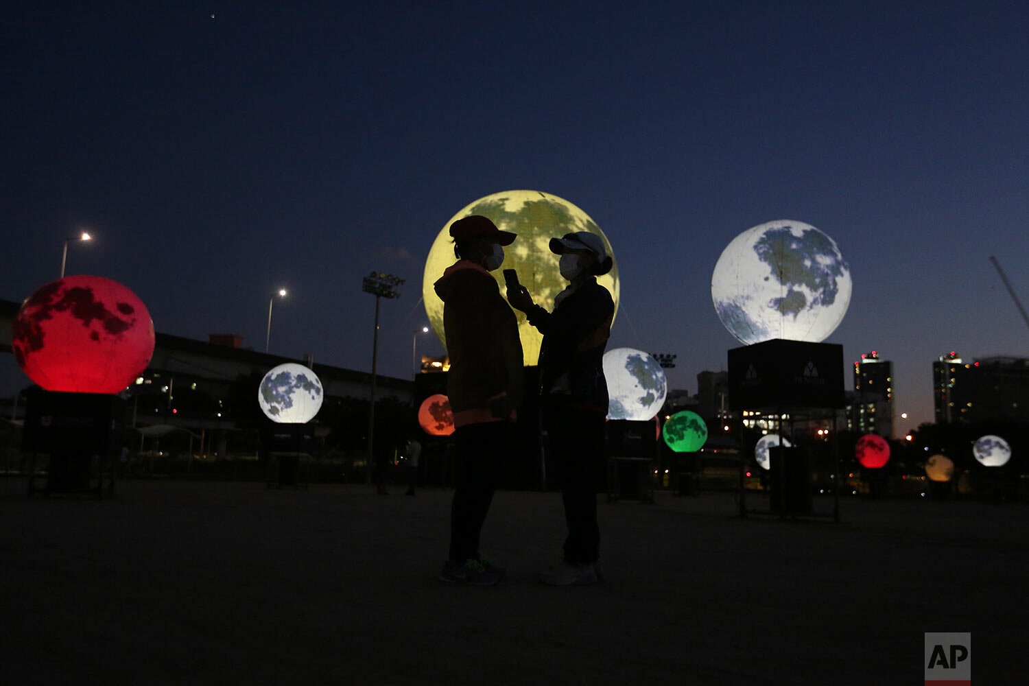  Women stand next to glowing full moon installations at a park in Seoul, South Korea, Friday, Sept. 18, 2020. (AP Photo/Ahn Young-joon) 