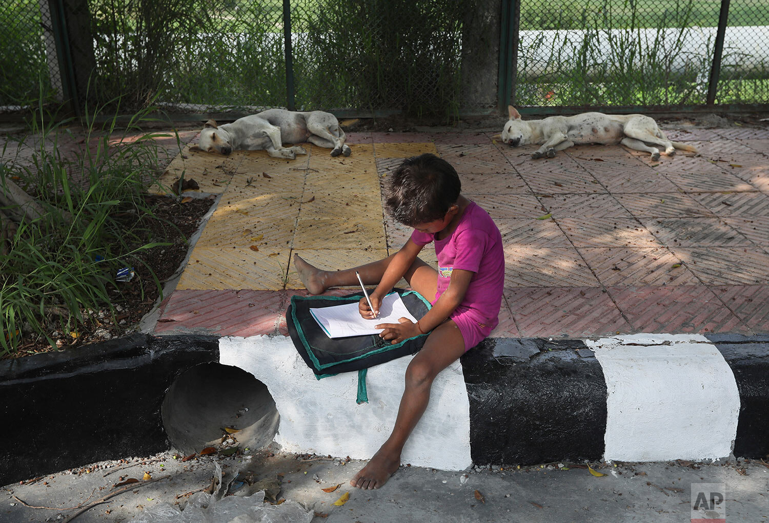 A child practices writing during a sidewalk class taught by an Indian couple, Veena Gupta and her husband Virendra Gupta, in New Delhi, India, on Sept. 3, 2020. (AP Photo/Manish Swarup) 