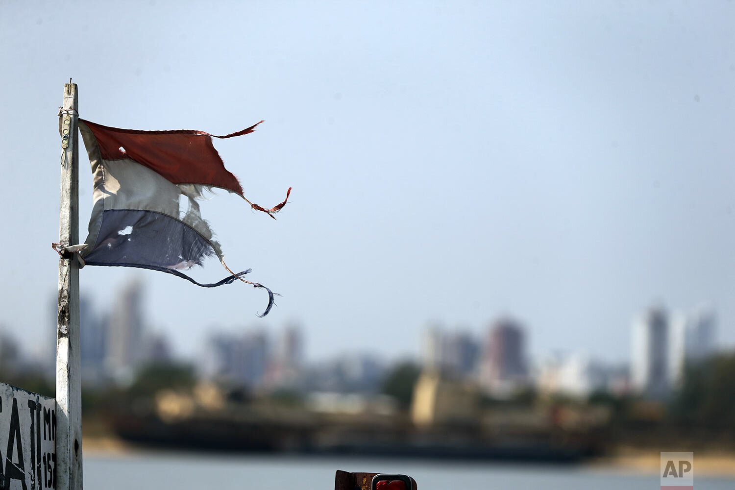  A worn Paraguayan flag flies across from the Chaco-i port where a barge sits on a dry bank in Asuncion, Paraguay, Thursday, Oct. 8, 2020. (AP Photo/Jorge Saenz) 