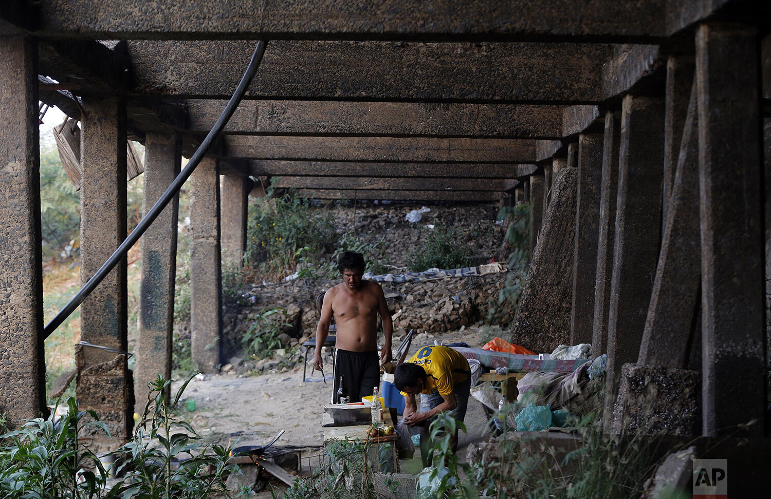  Homeless men cook under the main pier of the Paraguay River, devoid of water amid a drought in Asuncion, Paraguay, Wednesday, Oct. 7, 2020. (AP Photo/Jorge Saenz) 