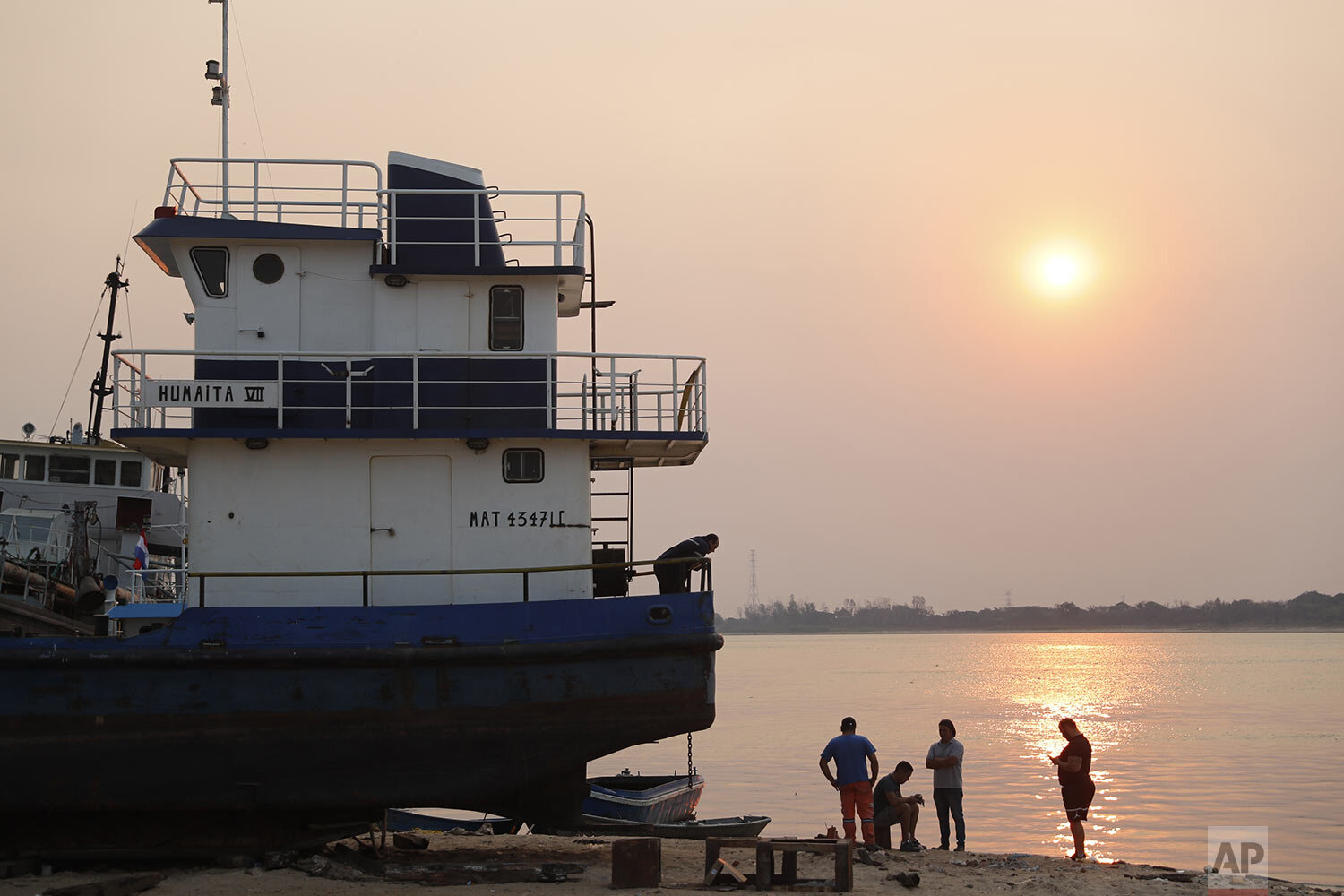  Workers rest at sunset on the shore of the Paraguay River in Asuncion, Paraguay, Wednesday, Oct. 7, 2020. (AP Photo/Jorge Saenz) 