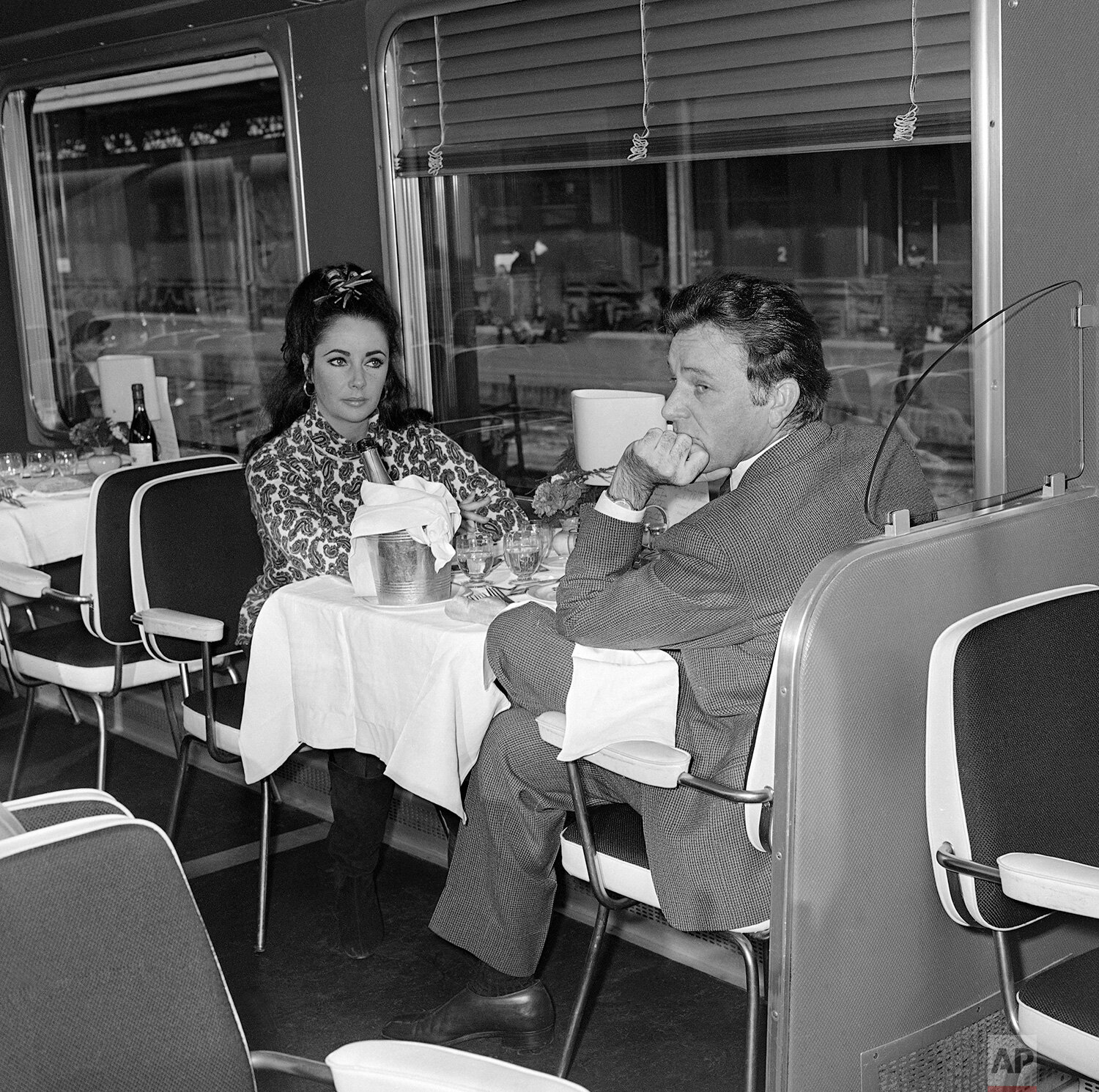  Elizabeth Taylor and her husband, Richard Burton have breakfast on board the Cisalpino train on Dec. 20, 1964. They are traveling to Gstaad, Switzerland where they will spend the holidays with their children. (AP Photo/Jean-Jacques Levy) 